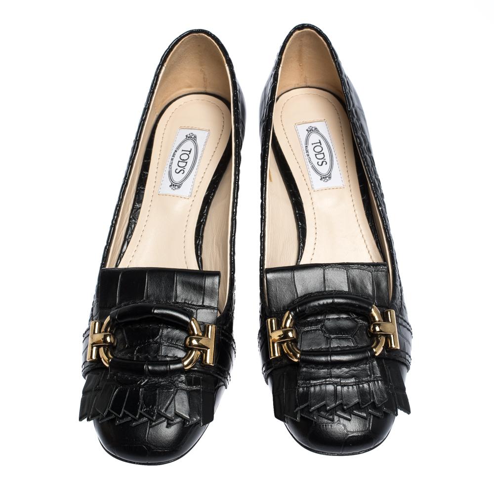 In a simple blend of elegance and style comes this pair of pumps from Tod's. They are covered in croc-embossed leather and shaped into covered toes graced with fringes and buckles. The pumps are elevated on block heels to give you the right lift of
