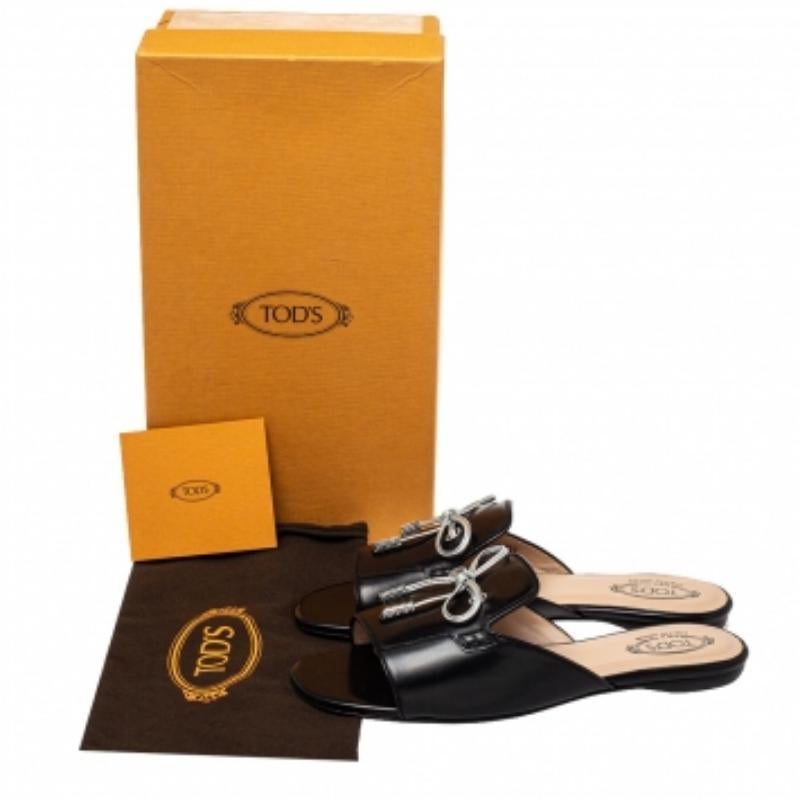 This chic and versatile pair of slides will go with any outfit. One of Tod's beautiful designs, these gorgeous open-toe flats are crafted from leather and styled with a crystal-embellished bow detailing at the front. The silver-tone hardware