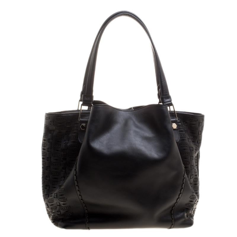 This shopping zip tote from Tod's is an ideal accessory for everyday use. Crafted from black leather, the bag sports perforations on the sides. It features dual top handles, a leather tassel accent and protective metal feet at the bottom. The zip