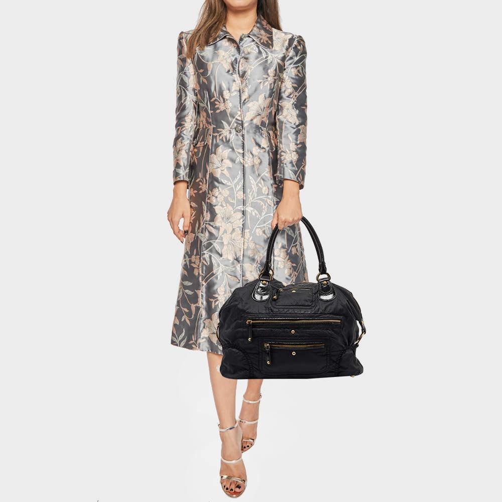 This Tod's Media D tote is the perfect carry-all to secure your daily essentials and that too in style. The black nylon exterior is accented with leather trims and gold-tone hardware. It features external pockets, two rolled leather handles, and