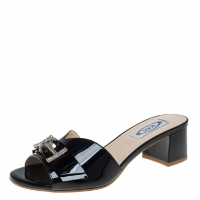 Perfectly blending comfort and glamorous style, these slide sandals from Tod's need to be owned by you! They are crafted from black patent leather in an open-toe silhouette and designed with the signature double 'T' accents embellished on the vamps.