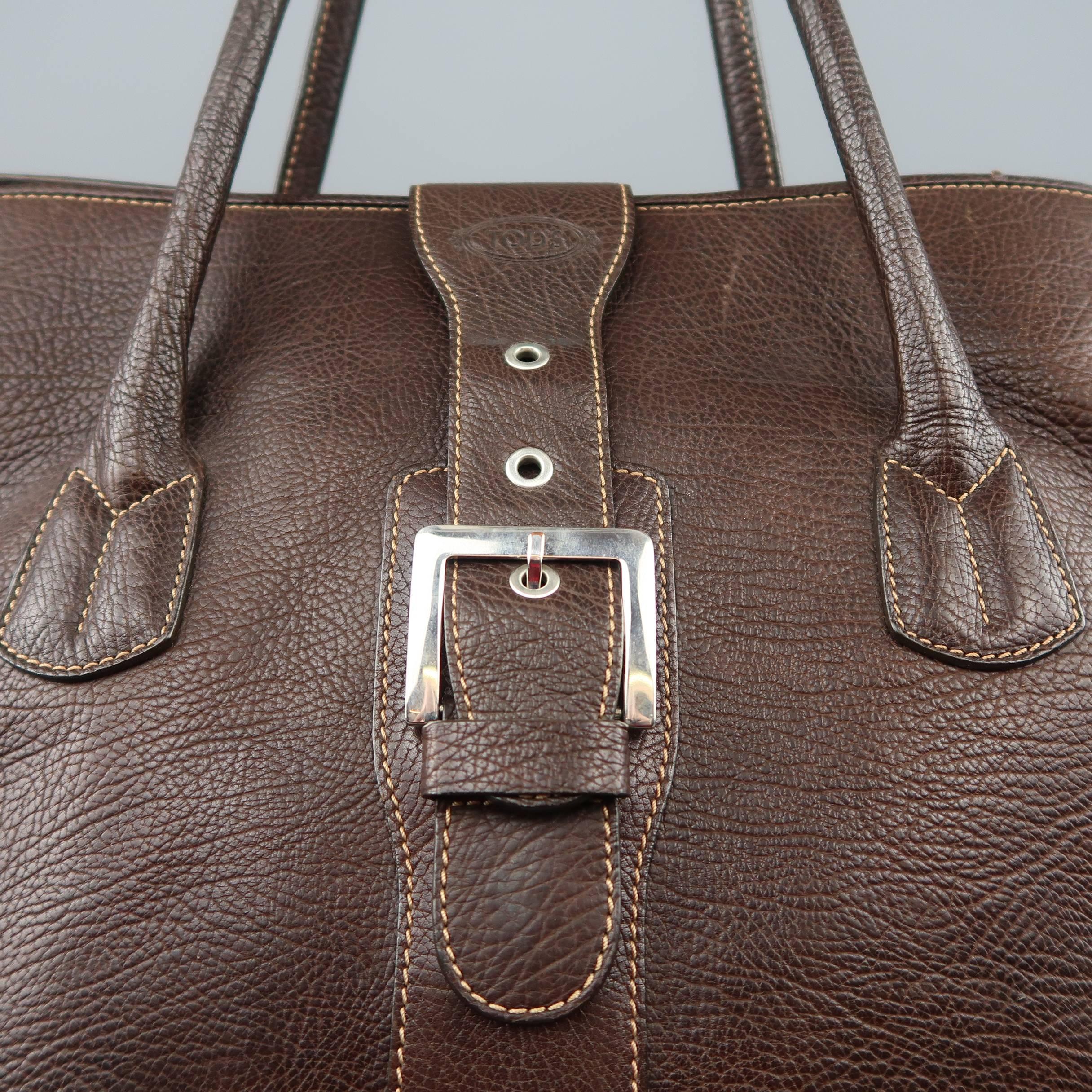 TOD'S weekender tote bag comes brown textured leather with double covered top handles, magnetic belt buckle top strap closure, and contrast stitch details throughout. Wear throughout. As-is.
 
Fair Pre-Owned Condition.
 
Measurements:
 
Length: