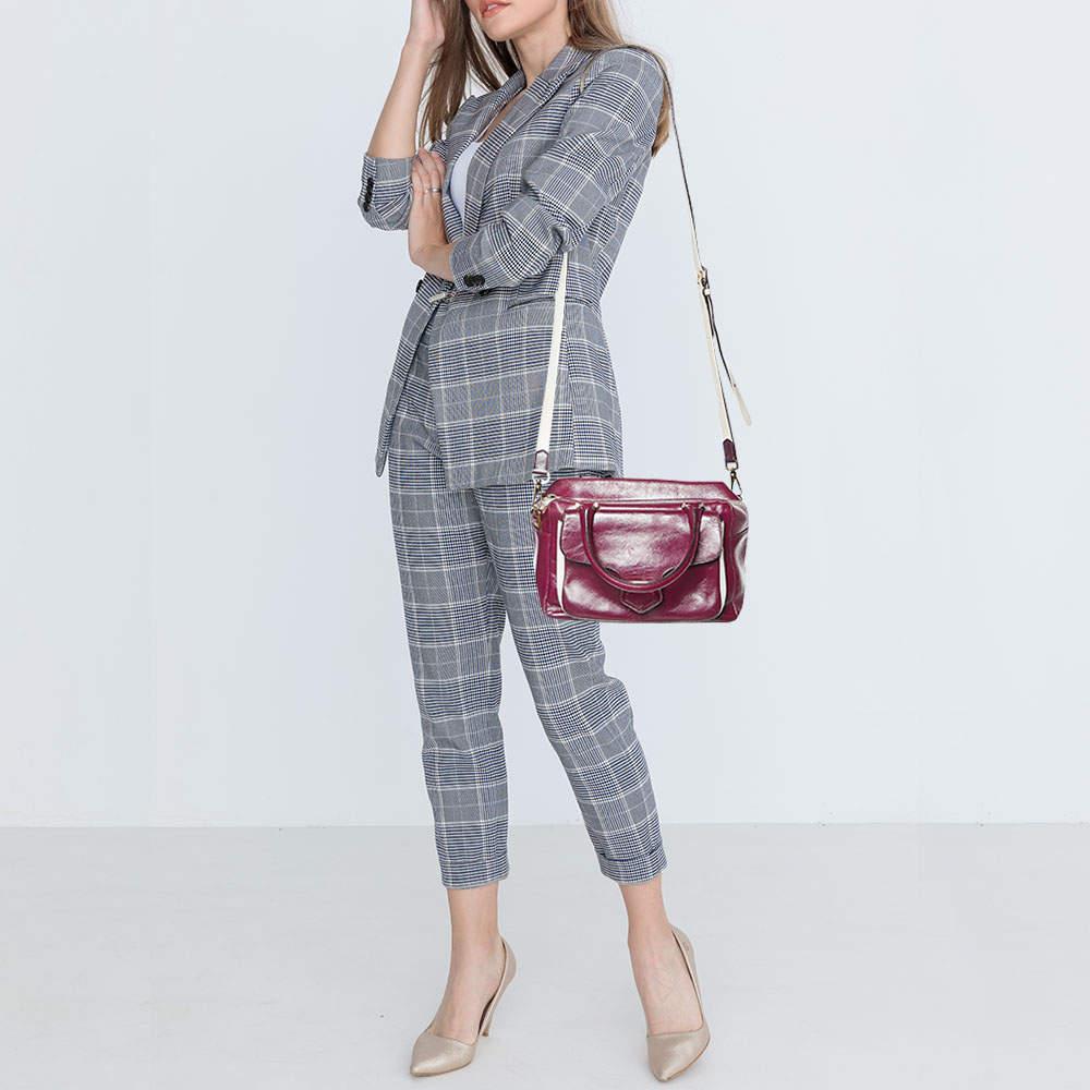 This Bowler bag from Tods is simple in design but high on style. Crafted from glossy leather the bag features double top handles a shoulder strap and protective feet at the bottom. It has an exterior flap pocket and a top zipper reveals a fabric