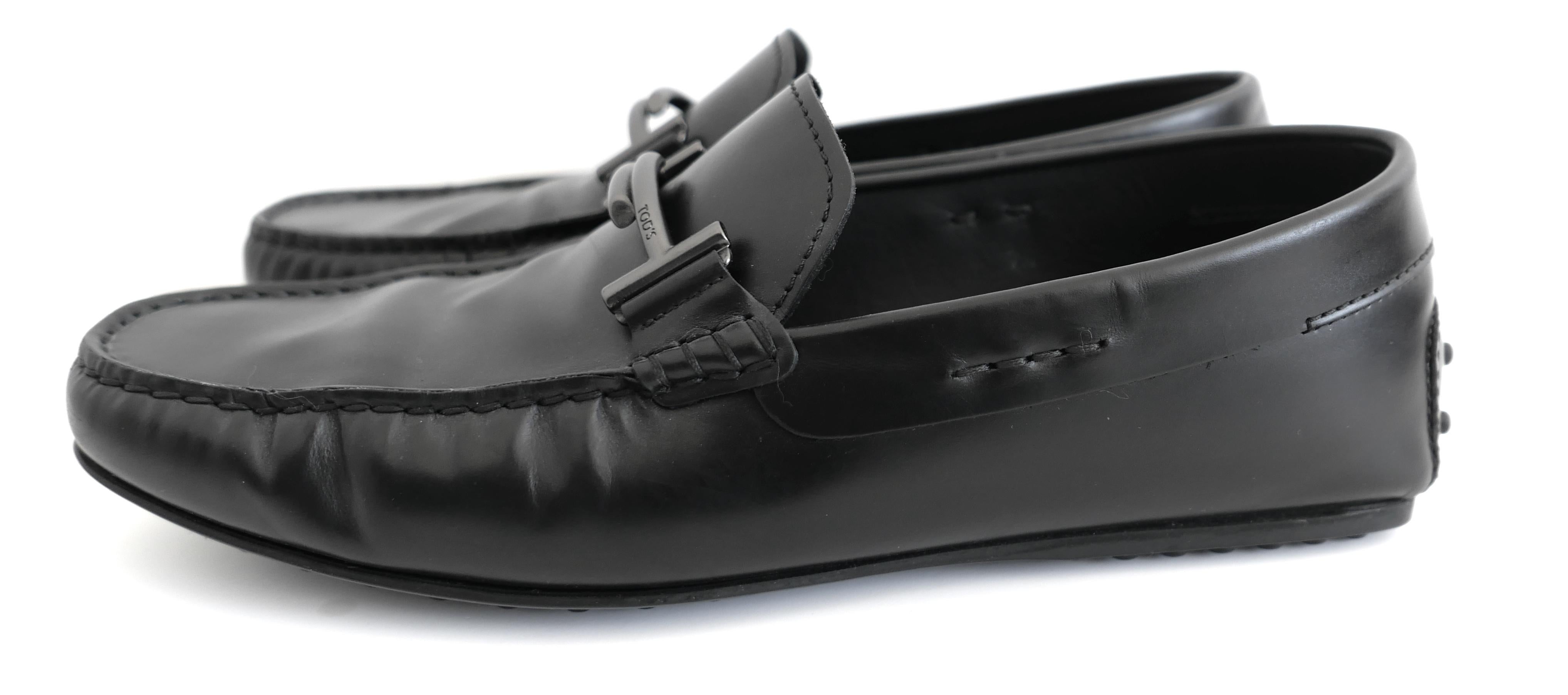 Mocasines Tod's City Gommino de lujo clásico. Comprado por 650 £ y usado en interiores una vez. Incluye 2 bolsas para el polvo. Magníficamente confeccionadas en piel negra lisa y brillante, incorporan los característicos herrajes en bronce de cañón,