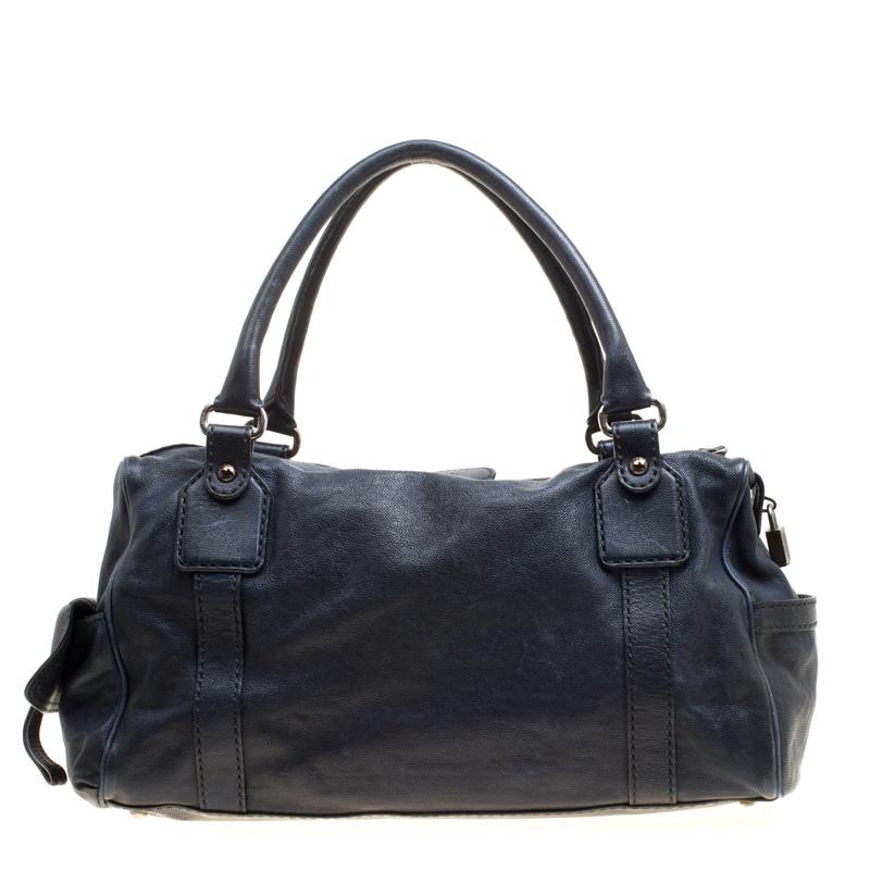 Stunning in a mix of dark blue leather and gold-tone hardware, this Tod's satchel is shaped into a lovely design. It has multiple exterior pockets, one main fabric compartment and two handles. Own this bag today and carry it with joy.

Includes: The