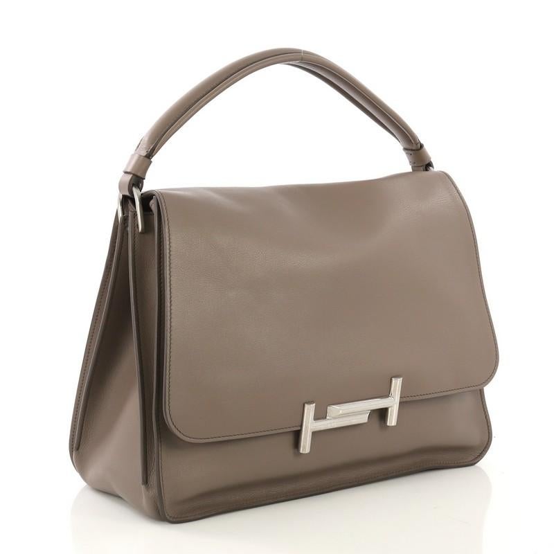 This Tod's Double T Crossbody Bag Leather Medium, crafted from taupe leather, features leather top handle, double T logo, exterior back pocket, and silver-tone hardware. Its magnetic snap closure opens to a black fabric interior.

Estimated Retail
