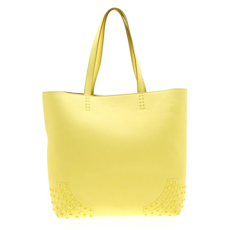 Carry this Tod's bag to flaunt a stylish look. Crafted from leather, the bag features pebble detailing on the bottom and two top handles. The suede interior enhances the utility of the bag. You will surely love this attractive light yellow piece,