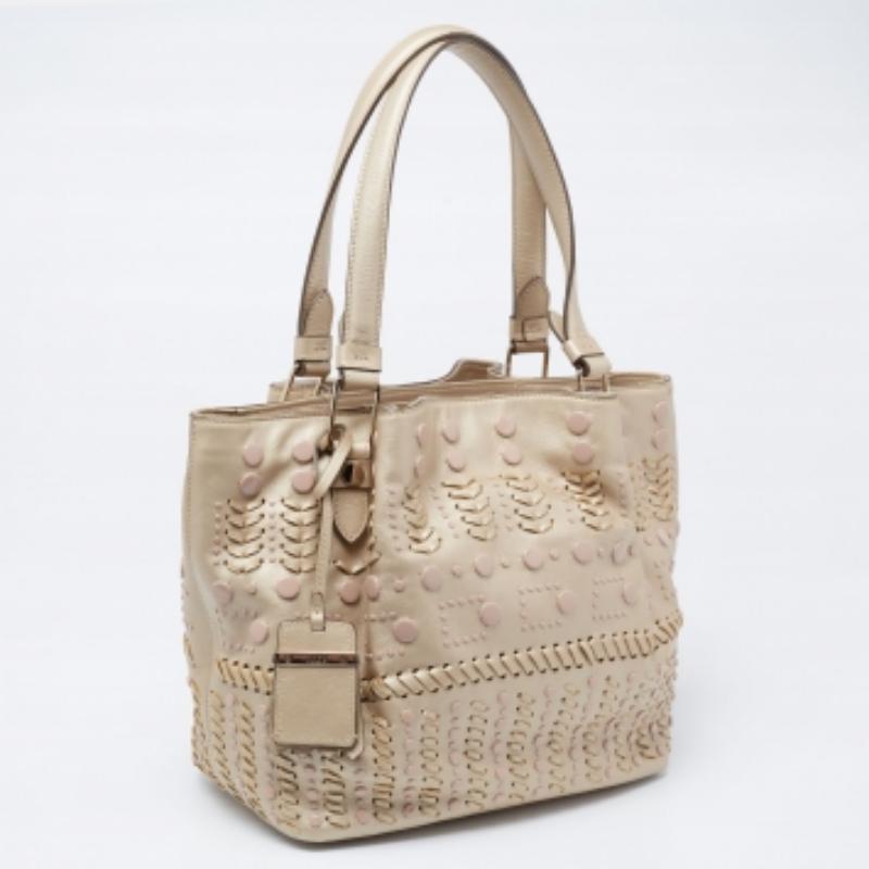 Tod's delivers a beautifully-made tote in metallic beige leather to assist you to work, lunch, or shopping. This tote is decorated with studs and sized spaciously for neatly housing your belongings. Two handles on top allow easy carrying options.