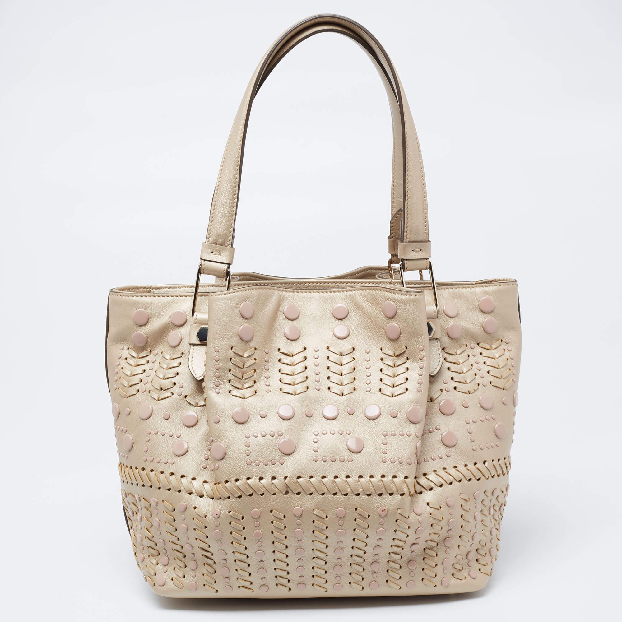 Tod's delivers a beautifully-made tote in metallic beige leather to assist you to work, lunch, or shopping. This tote is decorated with studs and sized spaciously for neatly housing your belongings. Two handles on top allow easy carrying