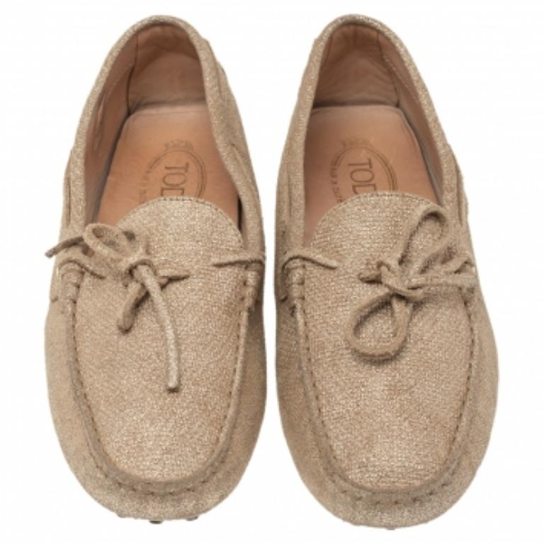 When you opt for Tod's shoes, you know that your feet are going to remain comfortable. These loafers from Tod's are created using metallic gold canvas with a bow motif detailing the upper. They are made in a slip-on style, making them great for