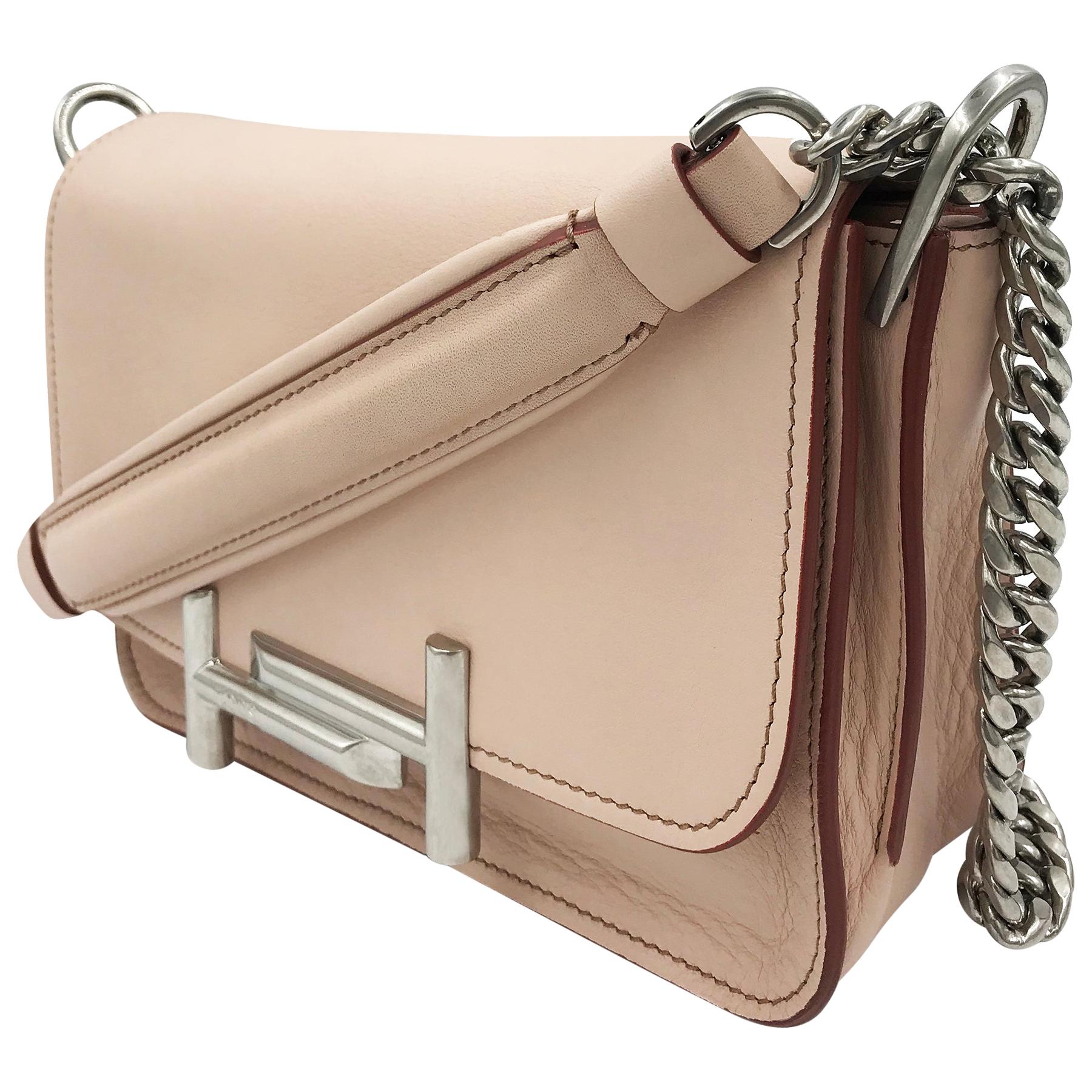 Double T mini shoulder bag by Tod's featuring pink leather with front flap and double T logo hardware closure. Comes with a double metal link chain and leather shoulder strap. Silver-tone metal hardware. Includes two interior compartments with two