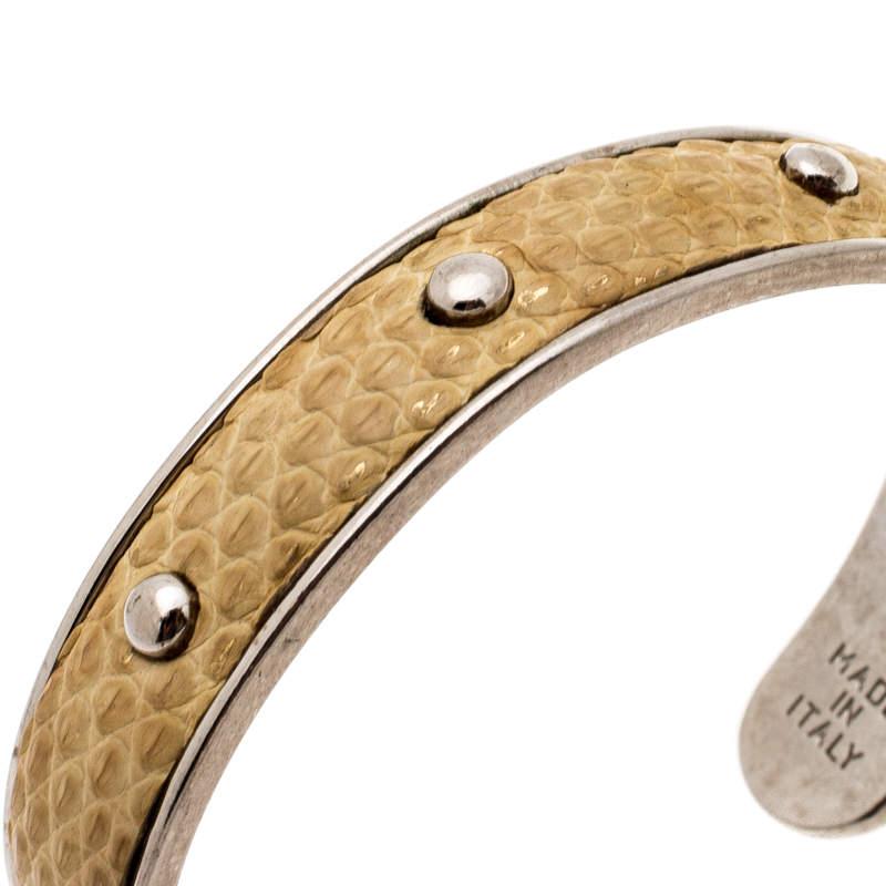 This Tod's bracelet features an open cuff silhouette making it easy to slip on and off. It is fashioned in a wide silver-tone metal body with mustard embossed leather inlay. Completed with stud detailing on the exterior, this simple piece looks best