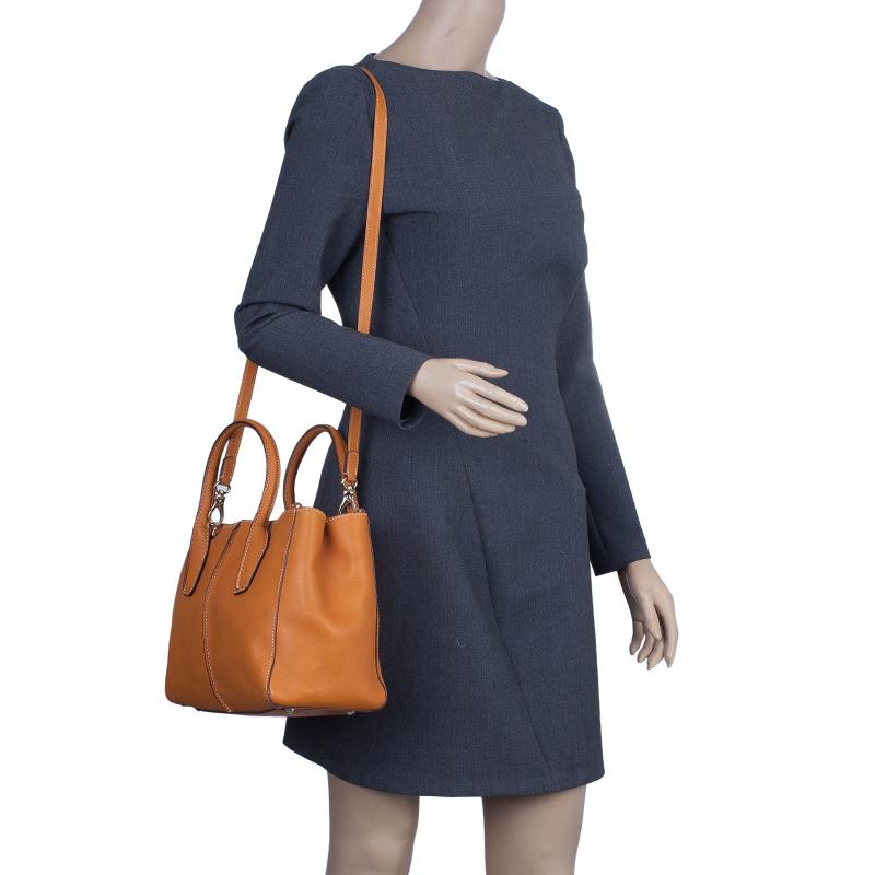 This versatile Tod's D-Styling Shopper Tote is made from supple orange leather with contrasting white stitching. It comes with double rolled leather handles, adjustable shoulder strap and side Tod's plaques. The interior is lined with fabric and
