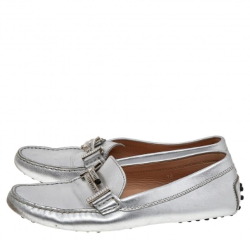 Questi magnifici mocassini di Tod's sono stati realizzati in pelle color argento. Presentano dettagli a T impreziositi sulla tomaia. Sono dotate dei caratteristici nastri in gomma sulle suole e sulle punte. Le solette sono foderate in pelle e