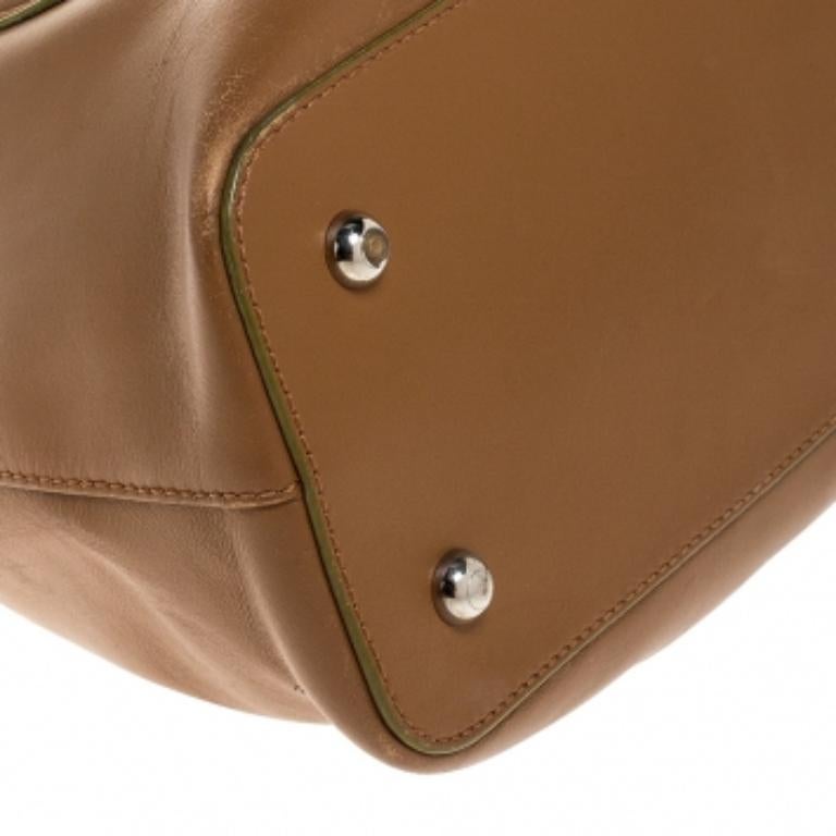 This satchel from Tod's is undoubtedly your next best buy! Tan in color, the bag features a striking silver-tone buckle fastening closure at the flap. The bag is accented with dual-rolled handles, protective metal feet and stitch details. The