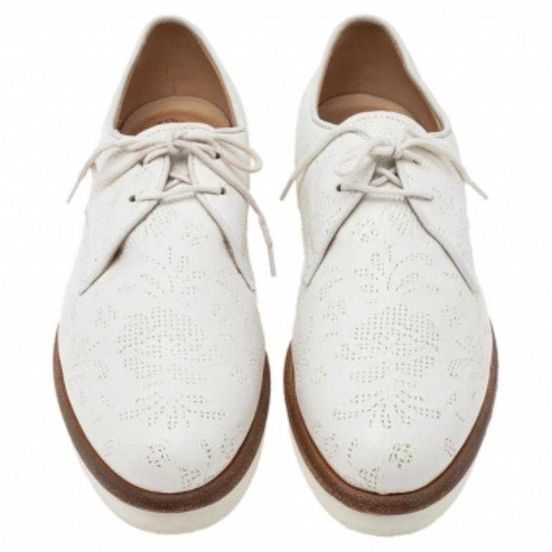 Crafted from leather in a pristine white shade, the exterior is detailed with intricate laser cuts and exudes the brand's refined flair. The derbies are complete with laces ties, sturdy soles, and round toes.