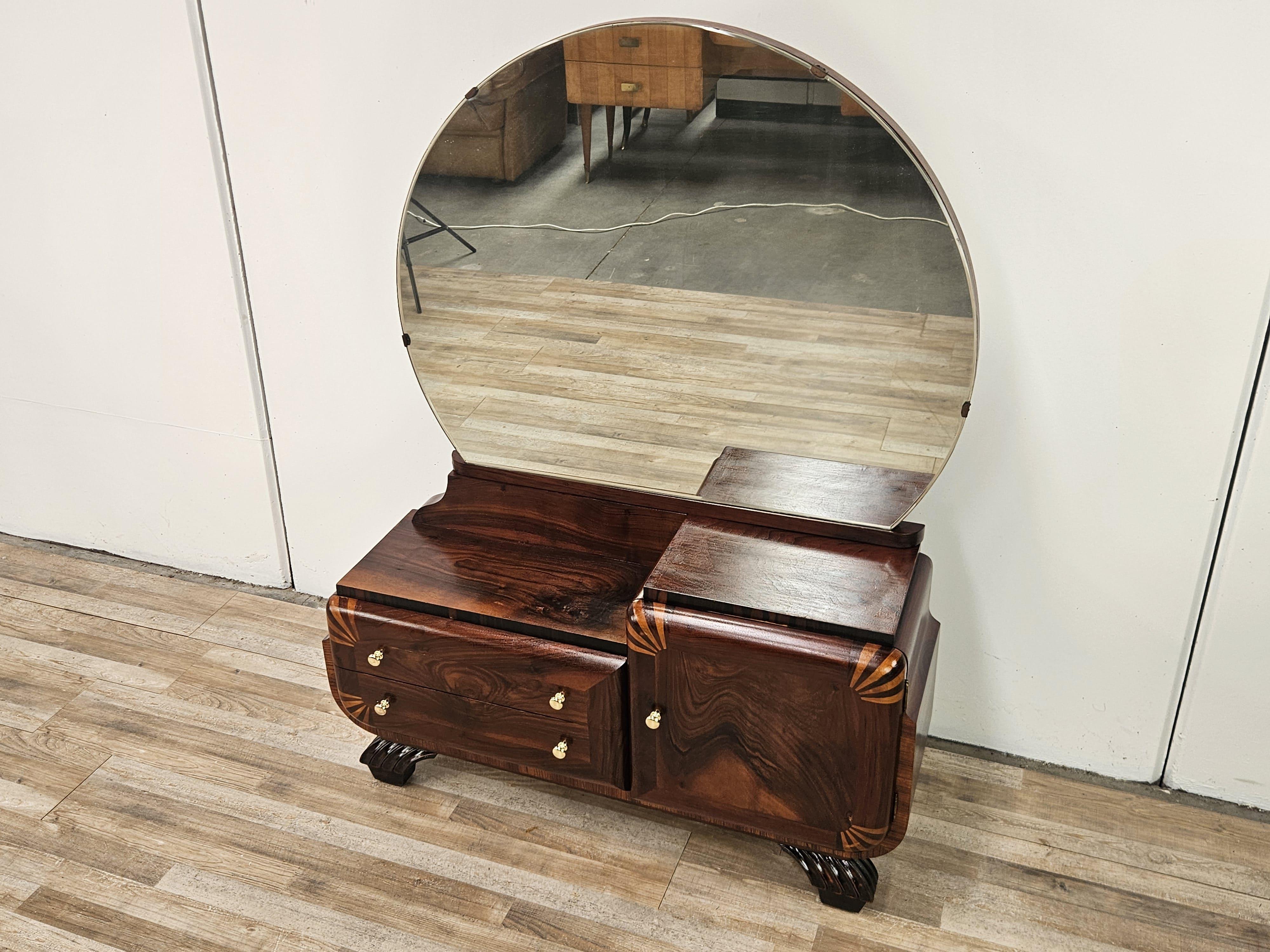Elegante e particolare toelette anni '40 di epoca Art Decò rivestita in radica di mogano con particolari in acero rosa e pomelli in ottone.

Da notare la specchiera a semicerchio originale dell'epoca come crea luce e contrasto. Mobile molto fine,