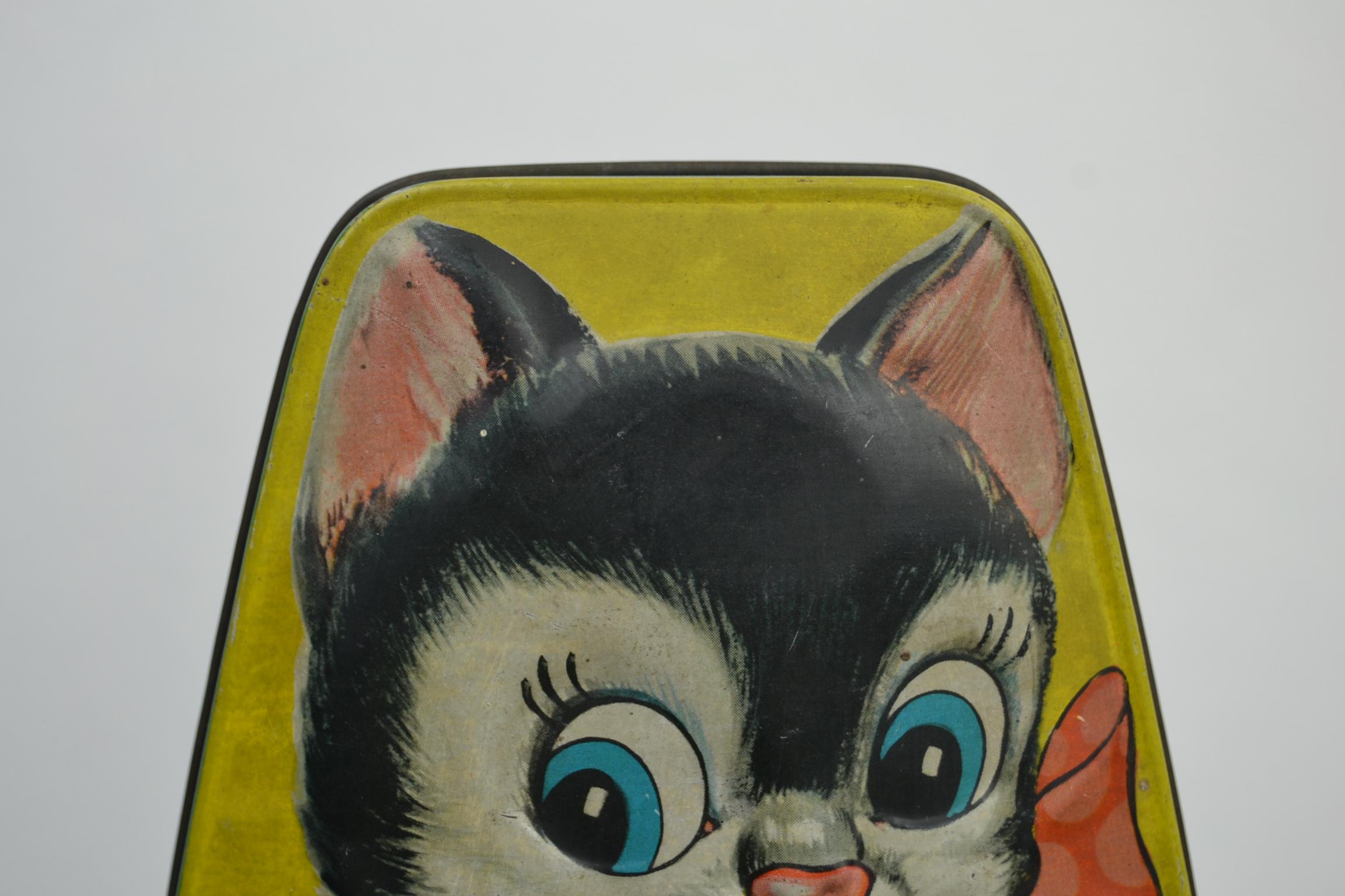 Cute vintage toffee tin box with 2 black and white cats.
The embossed tin box has a yellow background with cats on.
A mama cat with a red bow around the neck and holding a horseshoe;
the kitten holding a sign with the text: Good luck.
This