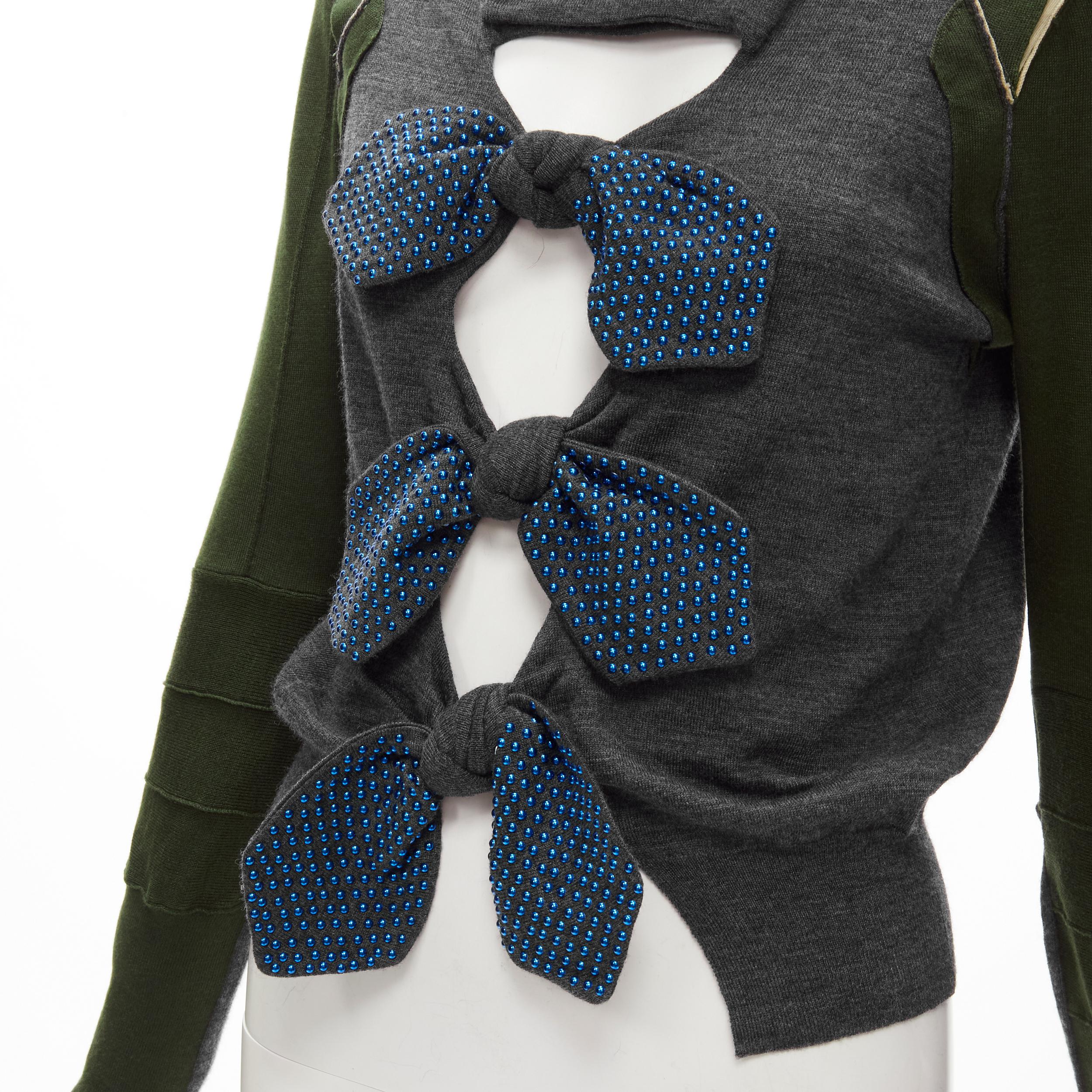 TOGA ARCHIVE blue studded bow patchwork sweater S 
Reference: ANWU/A00728 
Brand: Toga Archives 
Material: Feels like wool 
Color: Grey 
Pattern: Bow 
Extra Detail: Metallic blue stud bow detailing on bow. Deconstructed patchwork sleeves.
