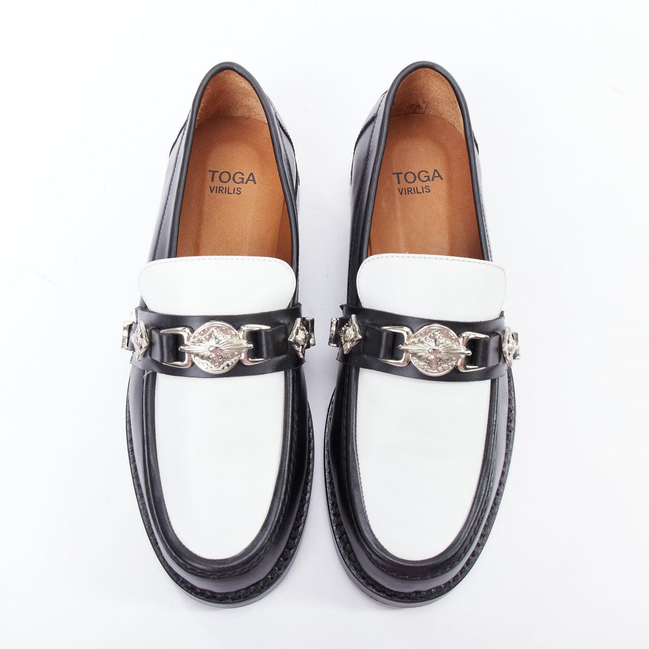 TOGA VIRILIS black white silver logo plague bicolor hard loafers EU39
Reference: JYLM/A00059
Brand: Toga Virilis
Material: Leather
Color: Black, White
Pattern: Solid
Closure: Slip On
Lining: Tan Brown Leather
Extra Details: Silver heel cap. Logo