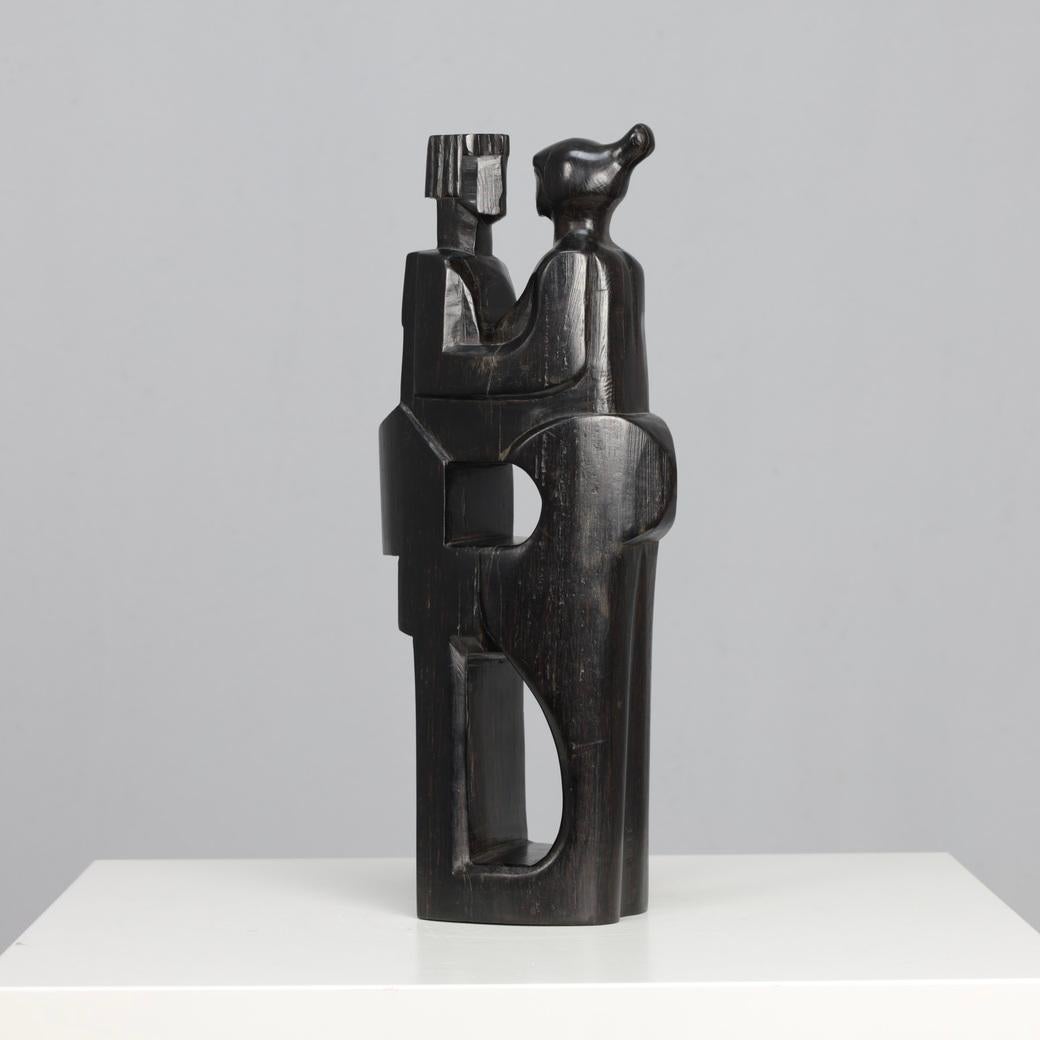 This hand-carved wooden sculpture by Jozef Kets captures a timeless moment of intimacy and human connection. Two stylized figures stand intertwined, reduced to pure geometric rhythm yet deeply emotional in presence. The piece reveals Kets’ mastery
