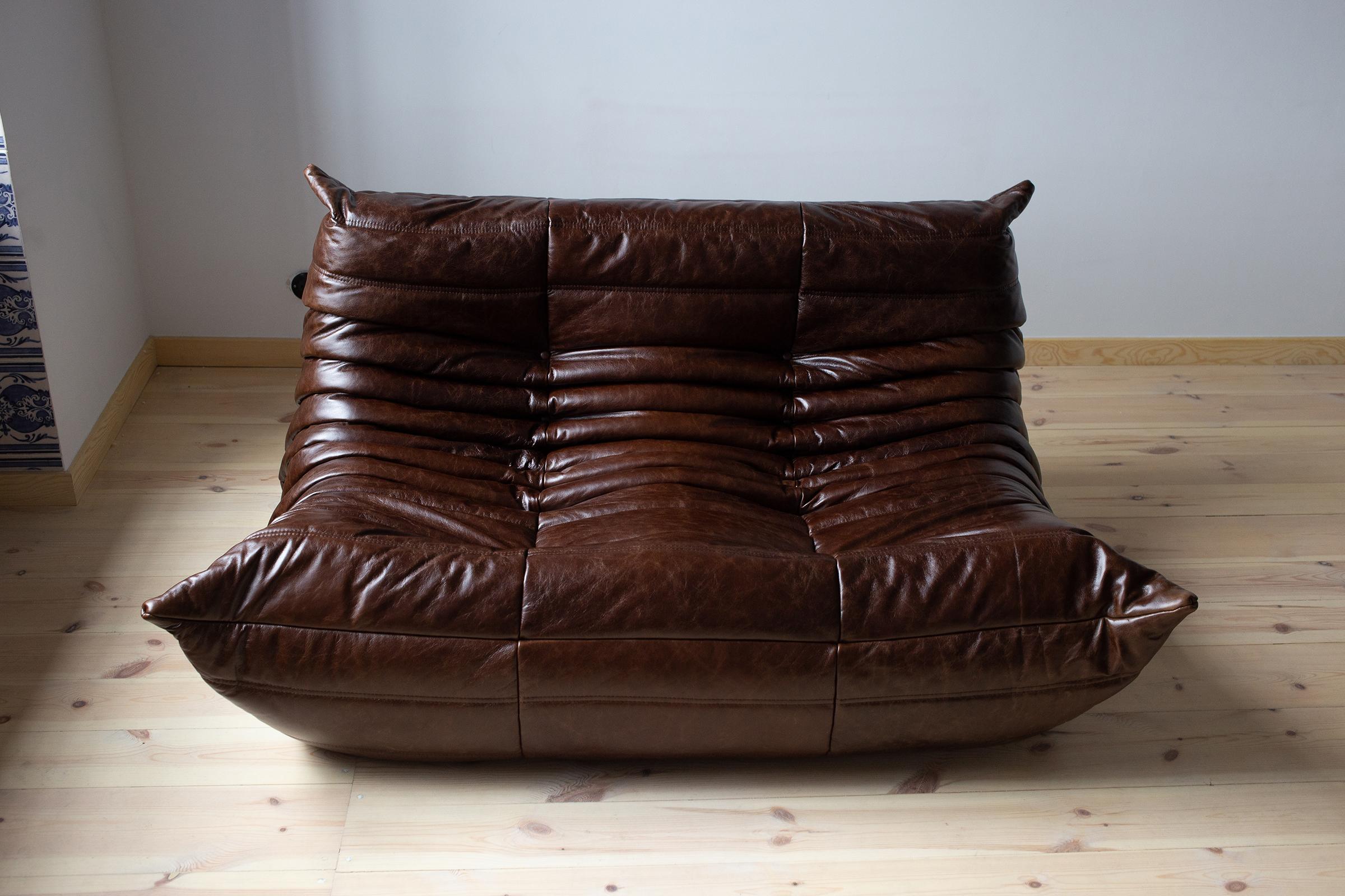 Diese zweisitzige Couch Togo wurde 1973 von Michel Ducaroy entworfen und von Ligne Roset in Frankreich hergestellt. Er wurde mit neuem braunem Leder aus Dubai bezogen (70 x 131 x 102 cm). Sie trägt das Original-Logo von Ligne Roset und einen echten