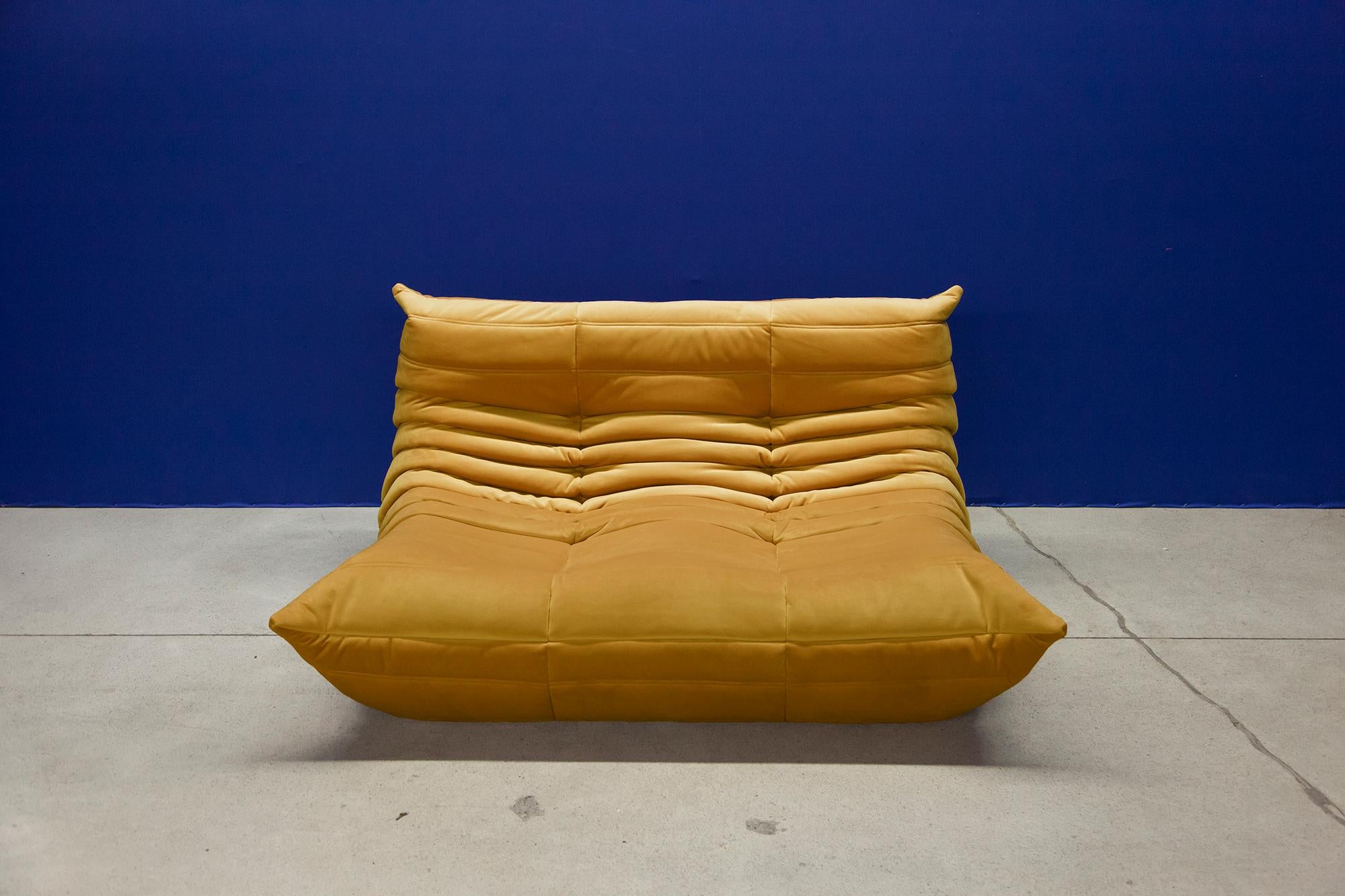 This two-seat Togo couch was designed by Michel Ducaroy in 1973 and was manufactured by Ligne Roset in France. It has been reupholstered in new golden yellow velvet (131 x 102 x 70 cm). It has the original Ligne Roset logo and genuine Ligne Roset