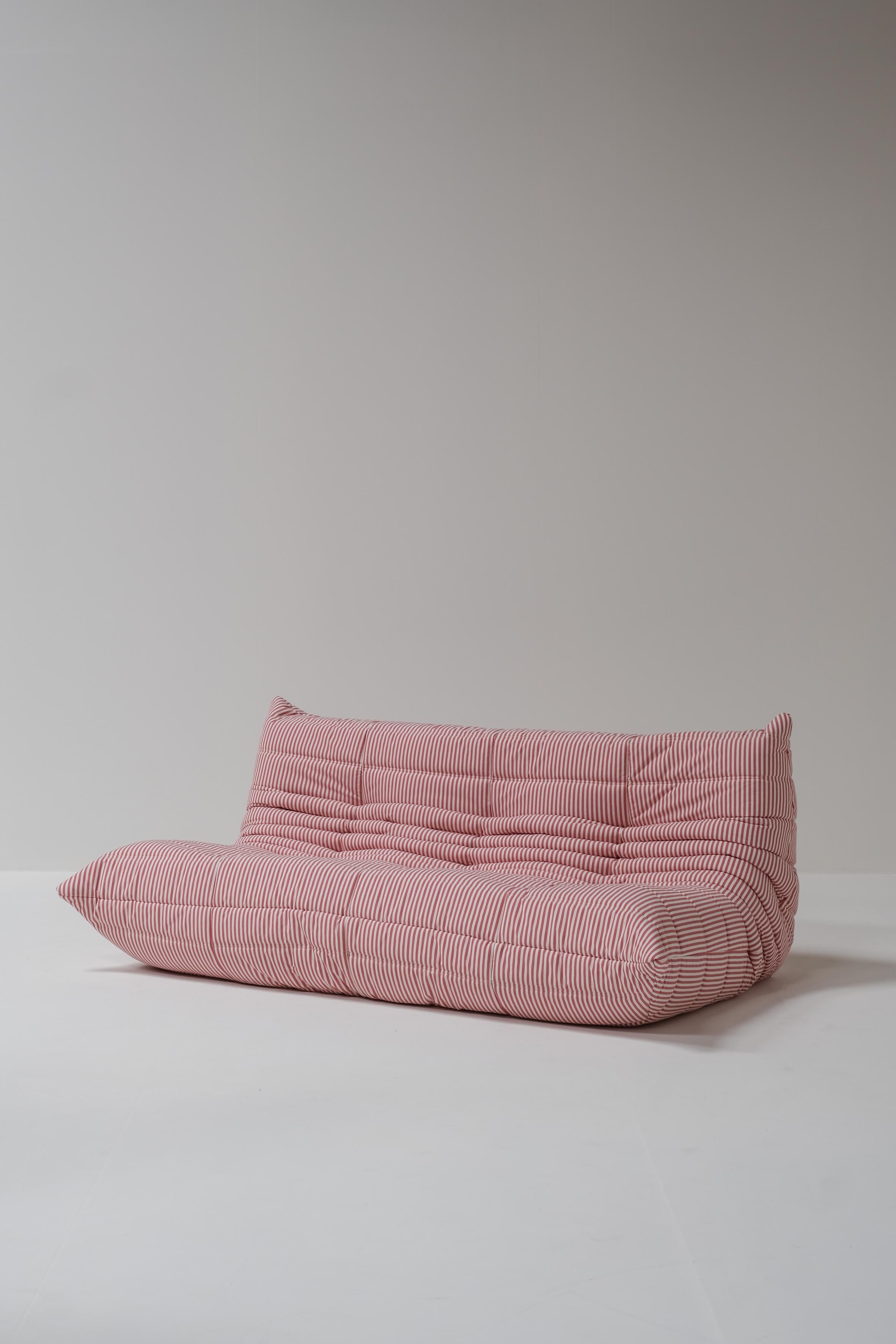 This vintage Togo 3-seater, designed by Michel Ducaroy for Ligne Roset in 1970, features newly upholstered red and white striped fabric. While its design is well-known, it remains a timeless piece that offers exceptional comfort.