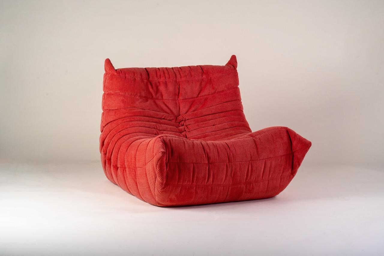An iconic Togo armchair designed by Michel Ducaroy for Ligne Roset in the 1970s, this piece embodies the relaxed spirit and radical design of its era. Upholstered in a striking red corduroy, the armchair is both visually rich and texturally