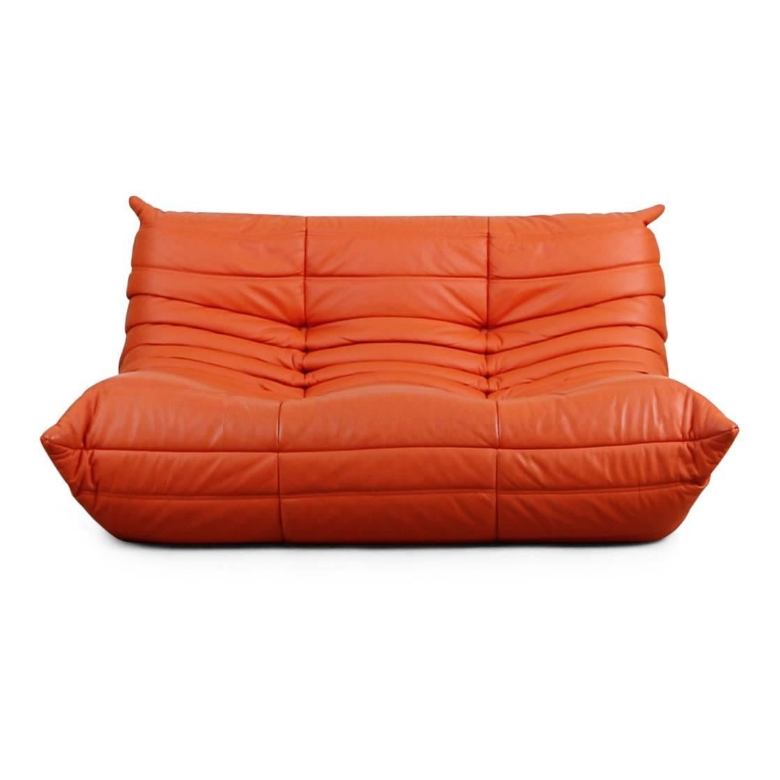 Timeless Ligne Roset Togo settee / loveseat designed by Michel Ducaroy in 1973. This eye-catching sofa features an ergonomic design with multiple density foam construction and generously quilted cover in a vibrant, zesty orange leather. 

This