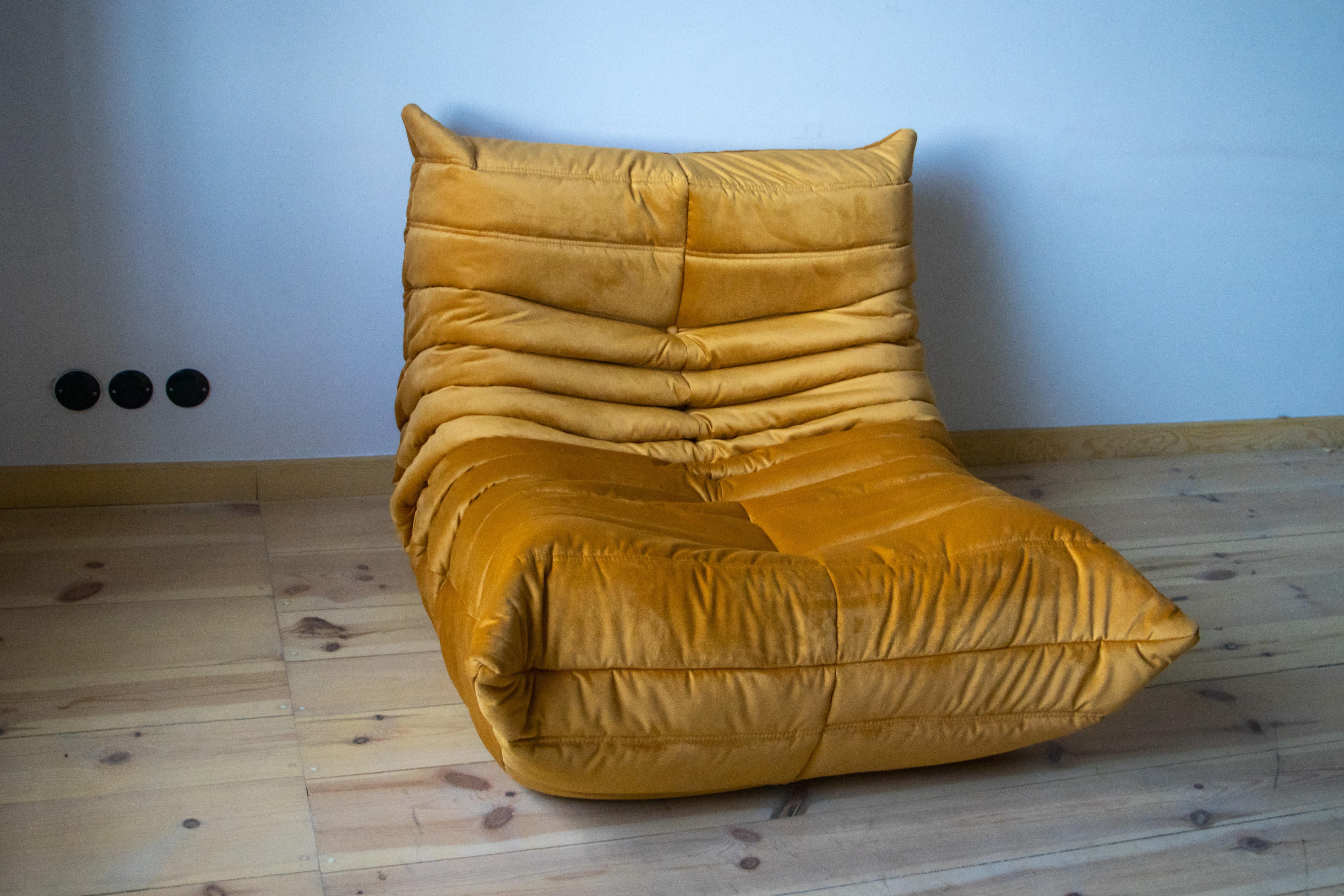 Diese Wohnzimmergarnitur Togo wurde 1973 von Michel Ducaroy entworfen und von Ligne Roset in Frankreich hergestellt. Sie wurde mit neuem goldfarbenem Samt bezogen und besteht aus folgenden Teilen: Eine dreisitzige Couch (70 x 174 x 102 cm), eine
