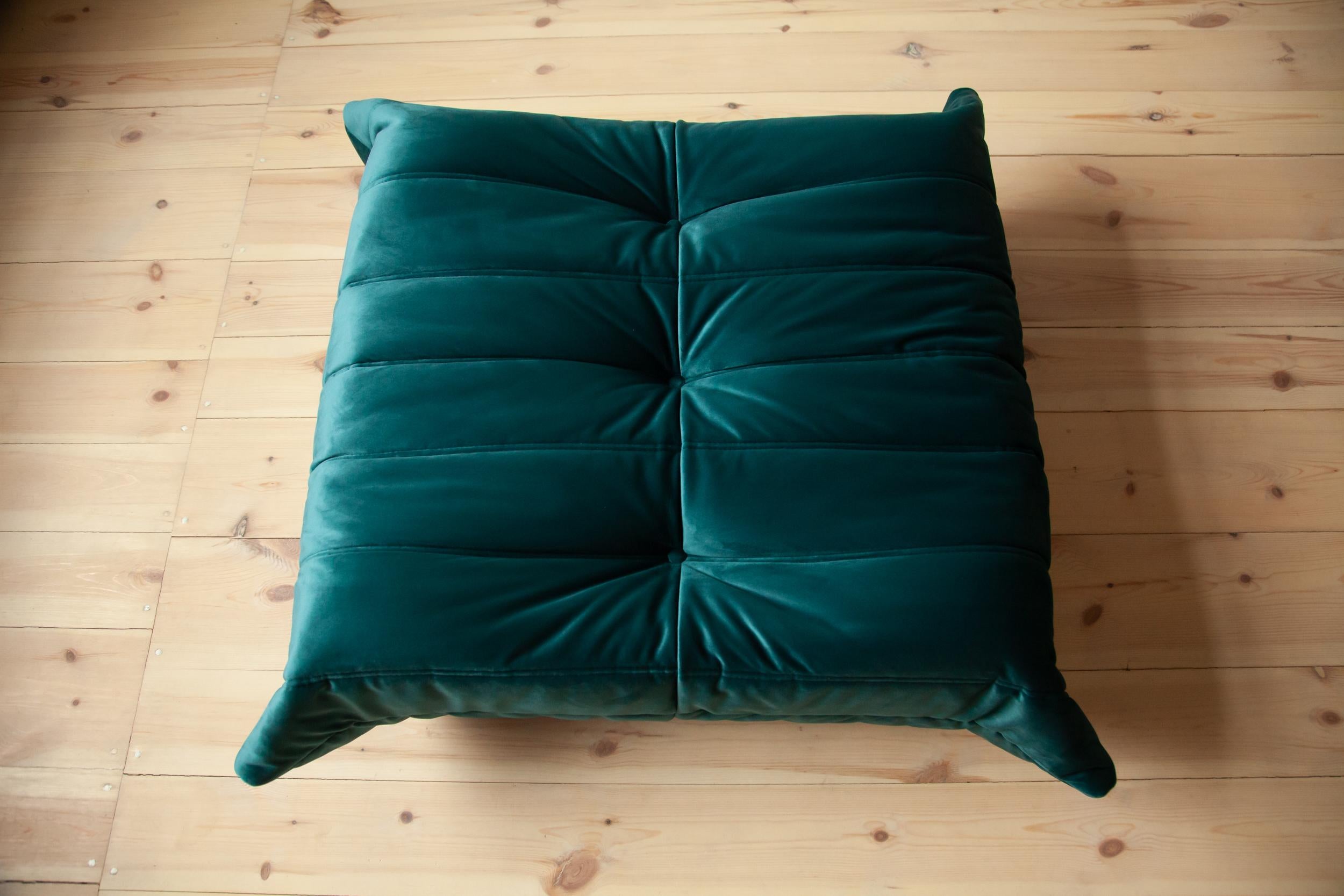 This Togo ottoman was designed by Michel Ducaroy in the 1973 and was manufactured by Ligne Roset in France. It has been reupholstered in new blue- green velvet (87 x 80 x 38 cm). It has the original Ligne Roset logo and genuine Ligne Roset bottom.