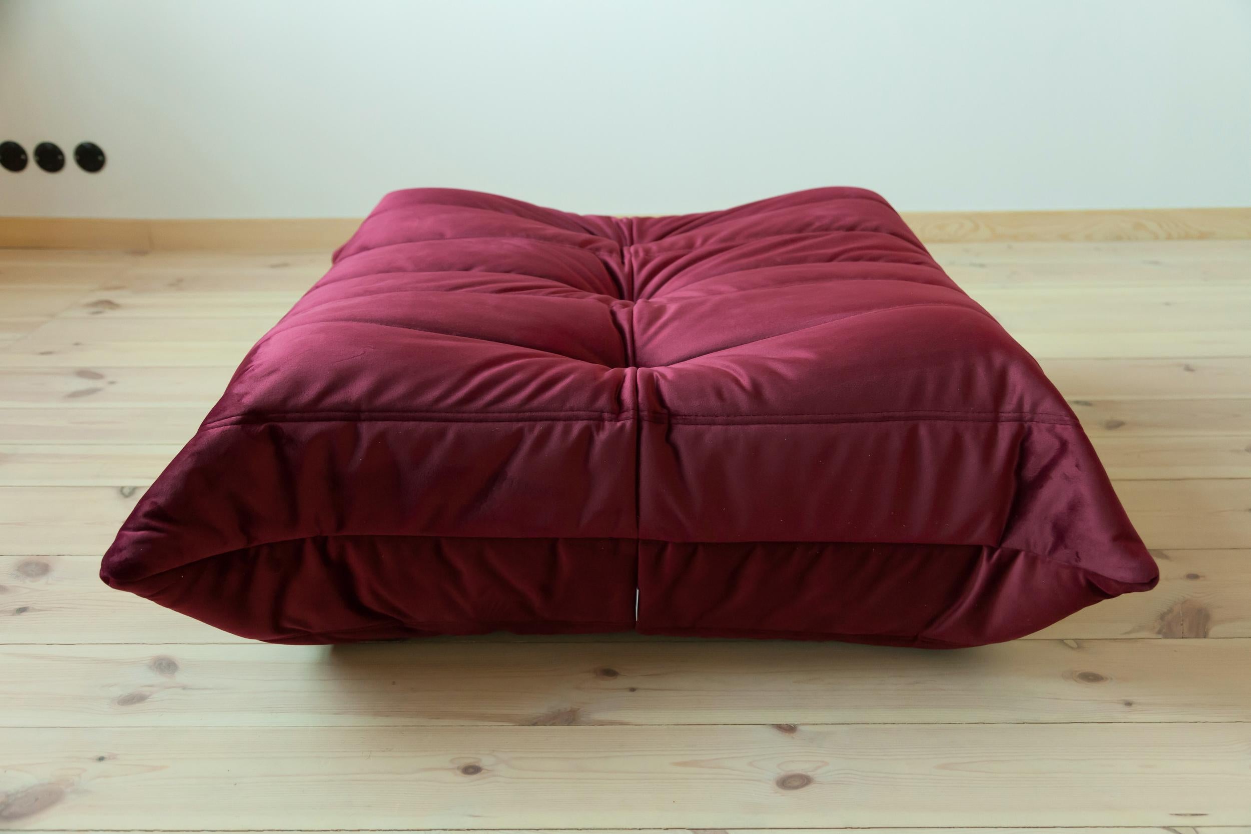 This Togo ottoman was designed by Michel Ducaroy in 1973 and was manufactured by Ligne Roset in France. It has been reupholstered in new burgundy velvet (87 x 80 x 34 cm). It has the original Ligne Roset logo and genuine Ligne Roset bottom.