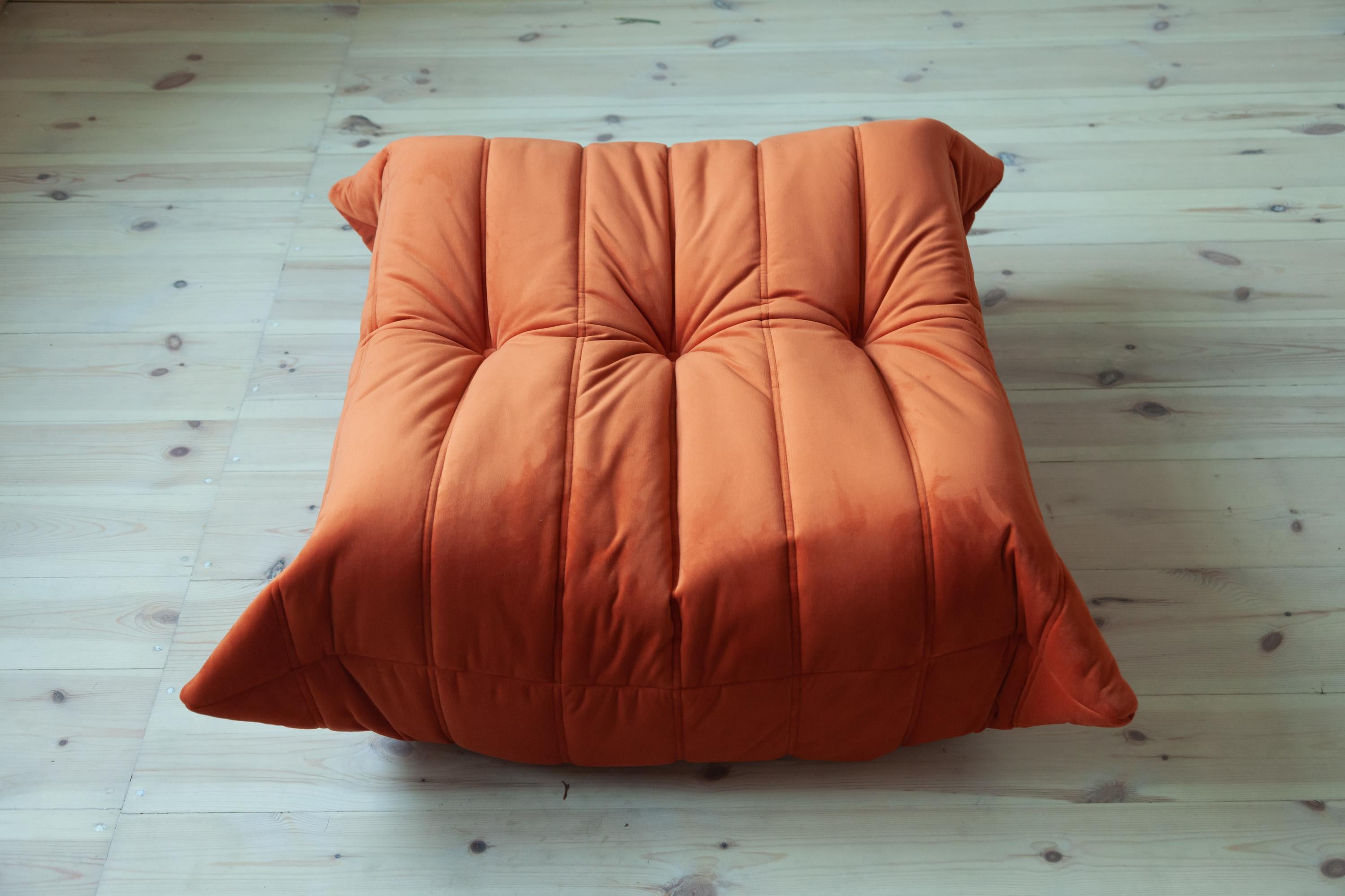 This Togo ottoman was designed by Michel Ducaroy in 1973 and was manufactured by Ligne Roset in France. It has been reupholstered in new orange velvet (87 x 80 x 34 cm). It has the original Ligne Roset logo and genuine Ligne Roset bottom.