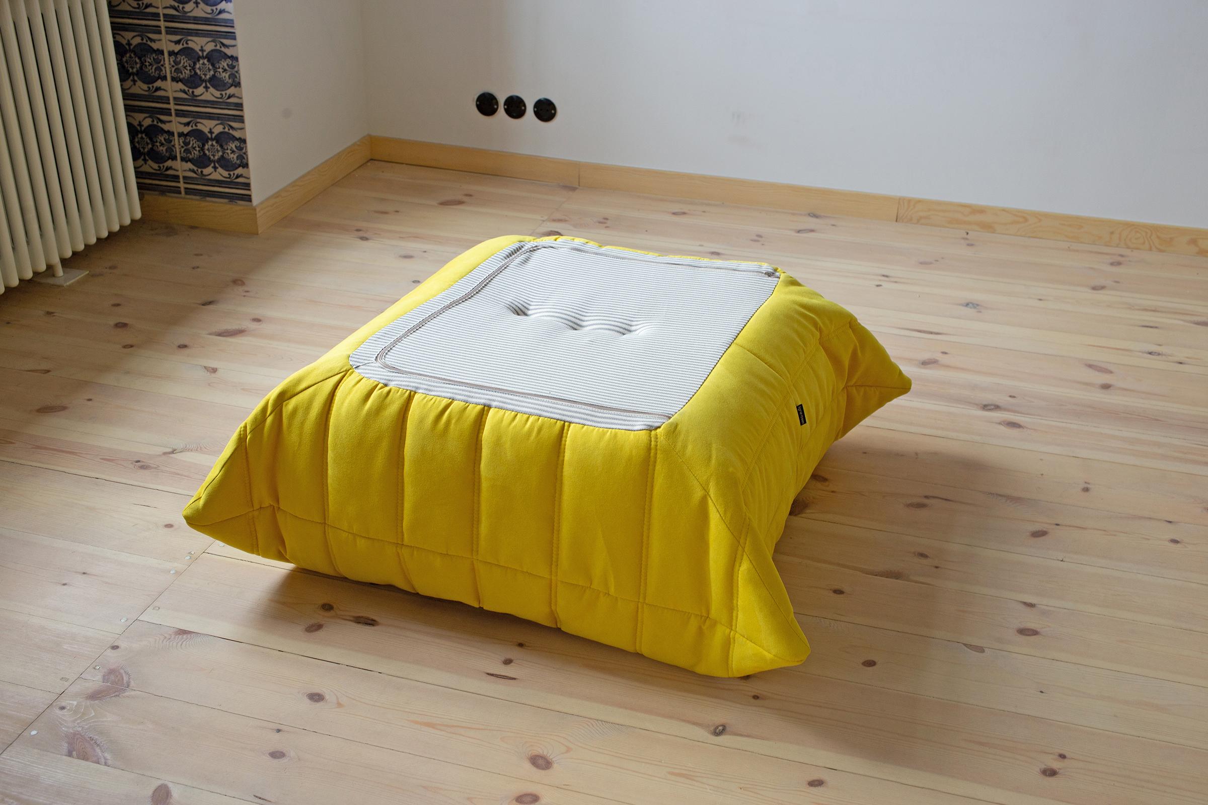 This Togo ottoman was designed by Michel Ducaroy in 1973 and was manufactured by Ligne Roset in France. It has been reupholstered in new yellow microfibre (87 x 80 x 34 cm). It has the original Ligne Roset logo and genuine Ligne Roset bottom.