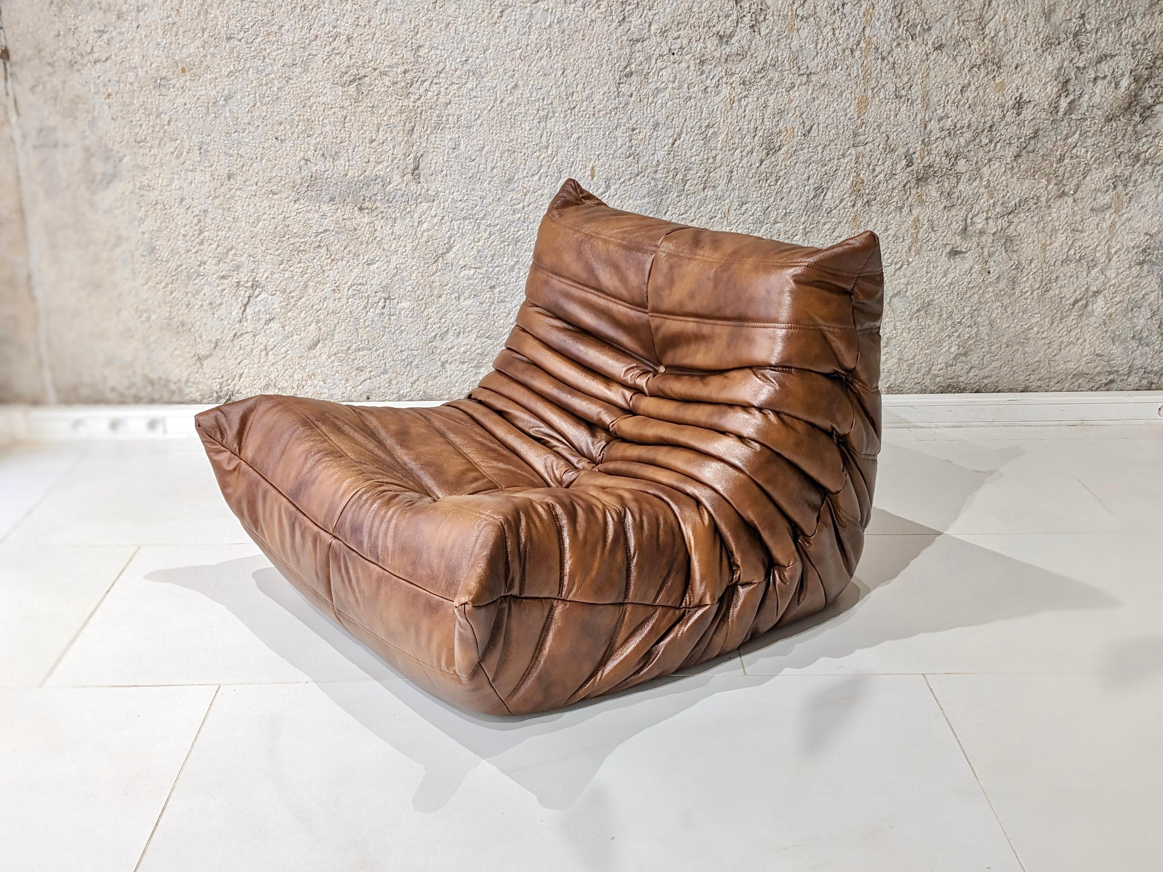 Togo set in brown leather by Michel Ducaroy for Ligne Roset. circa 2000. 
The set consists of an armchair, a corner, a two-seater sofa and a footstool. 
Very good condition. The set has been reupholstered. The underside and the label are original
