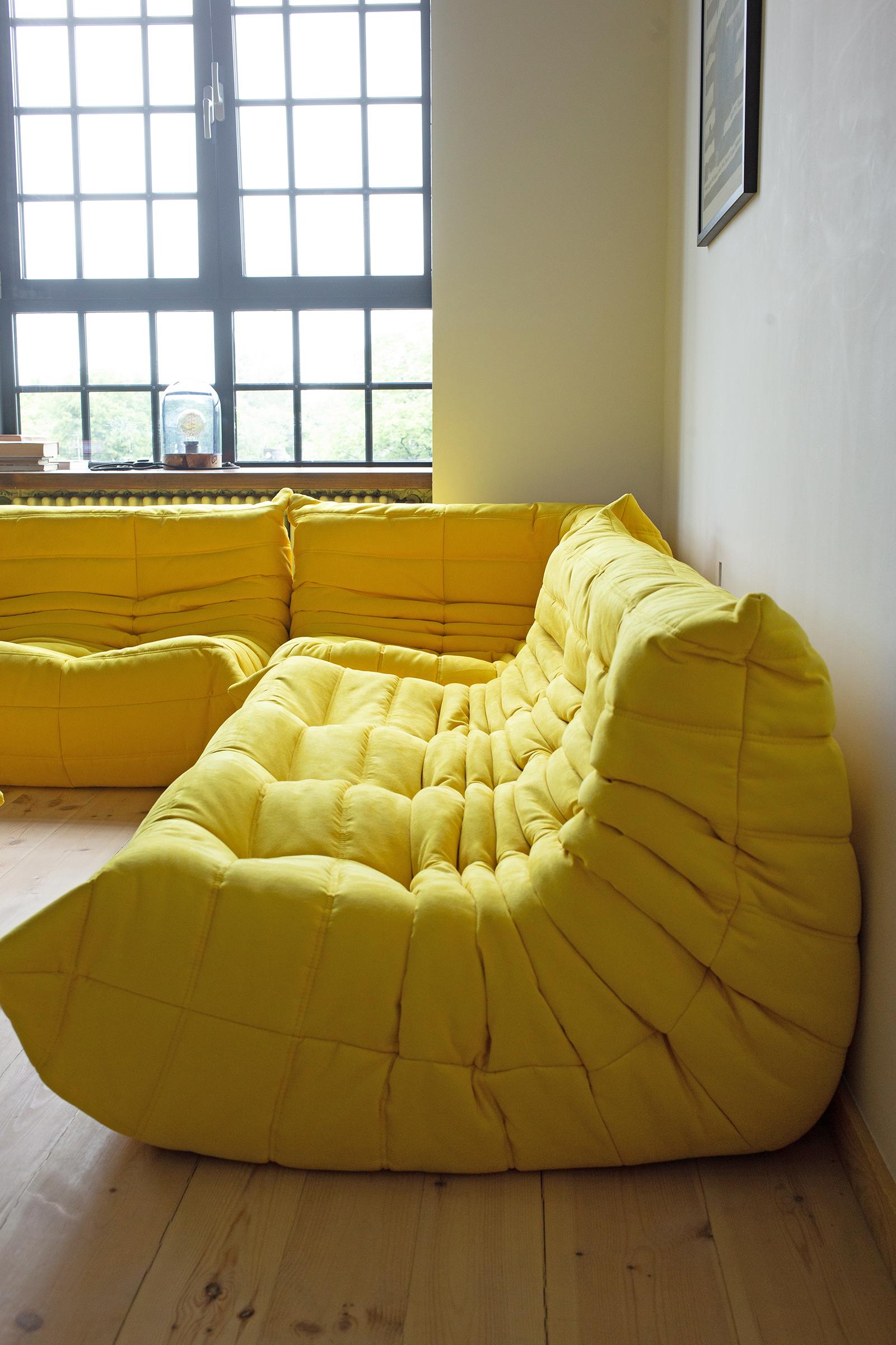 This Togo living room set was designed by Michel Ducaroy in 1973 and was manufactured by Ligne Roset in France. It has been reupholstered in new, great quality yellow microfiber and is made up of the following pieces: One three-seat couch (70 x 174