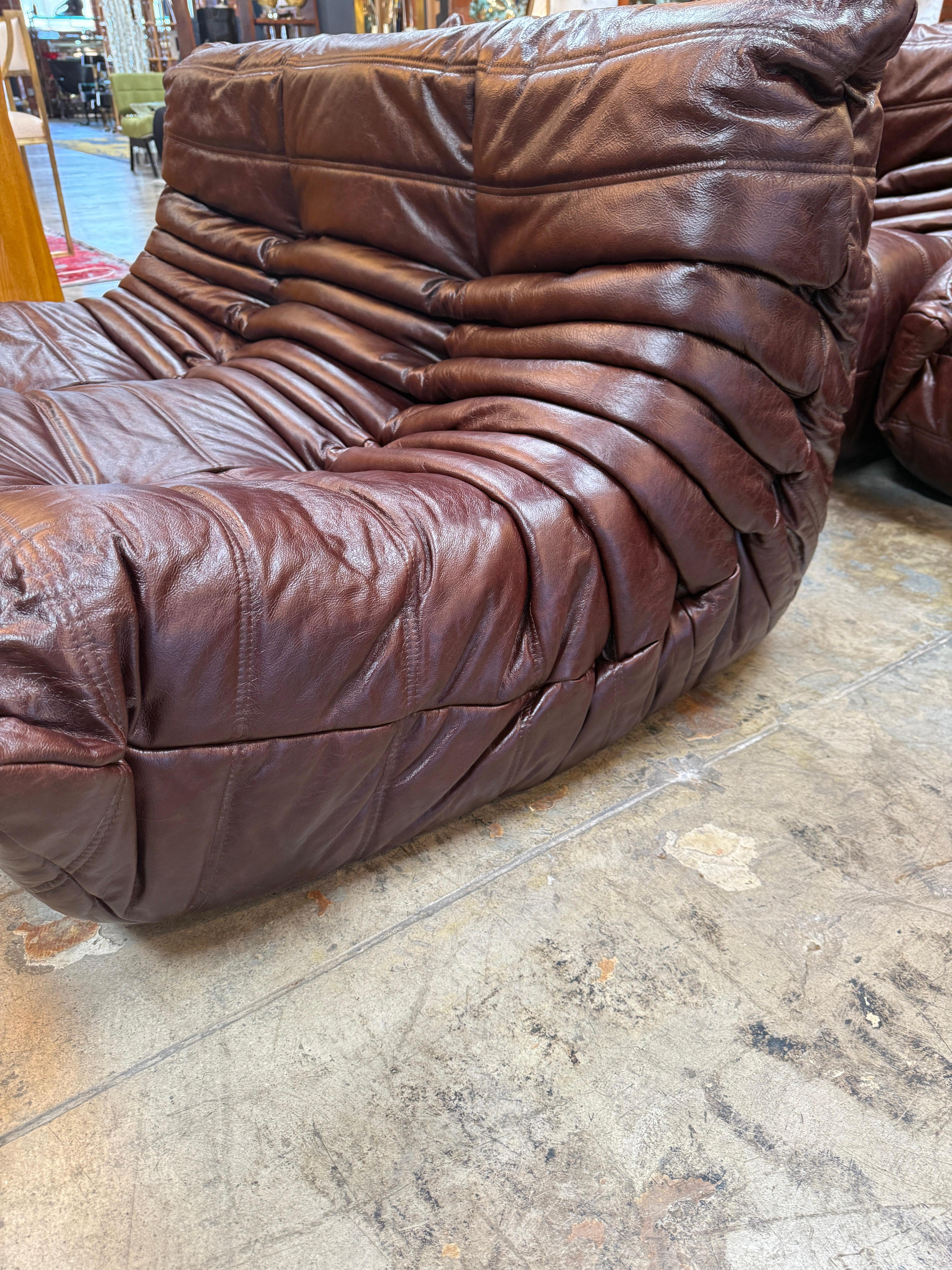 This stunning five-piece Togo sofa set in rich burgundy leather brings an iconic blend of form, function, and timeless style to any space. Designed by Michel Ducaroy for Ligne Roset, the Togo’s unmistakable silhouette is defined by its low-slung