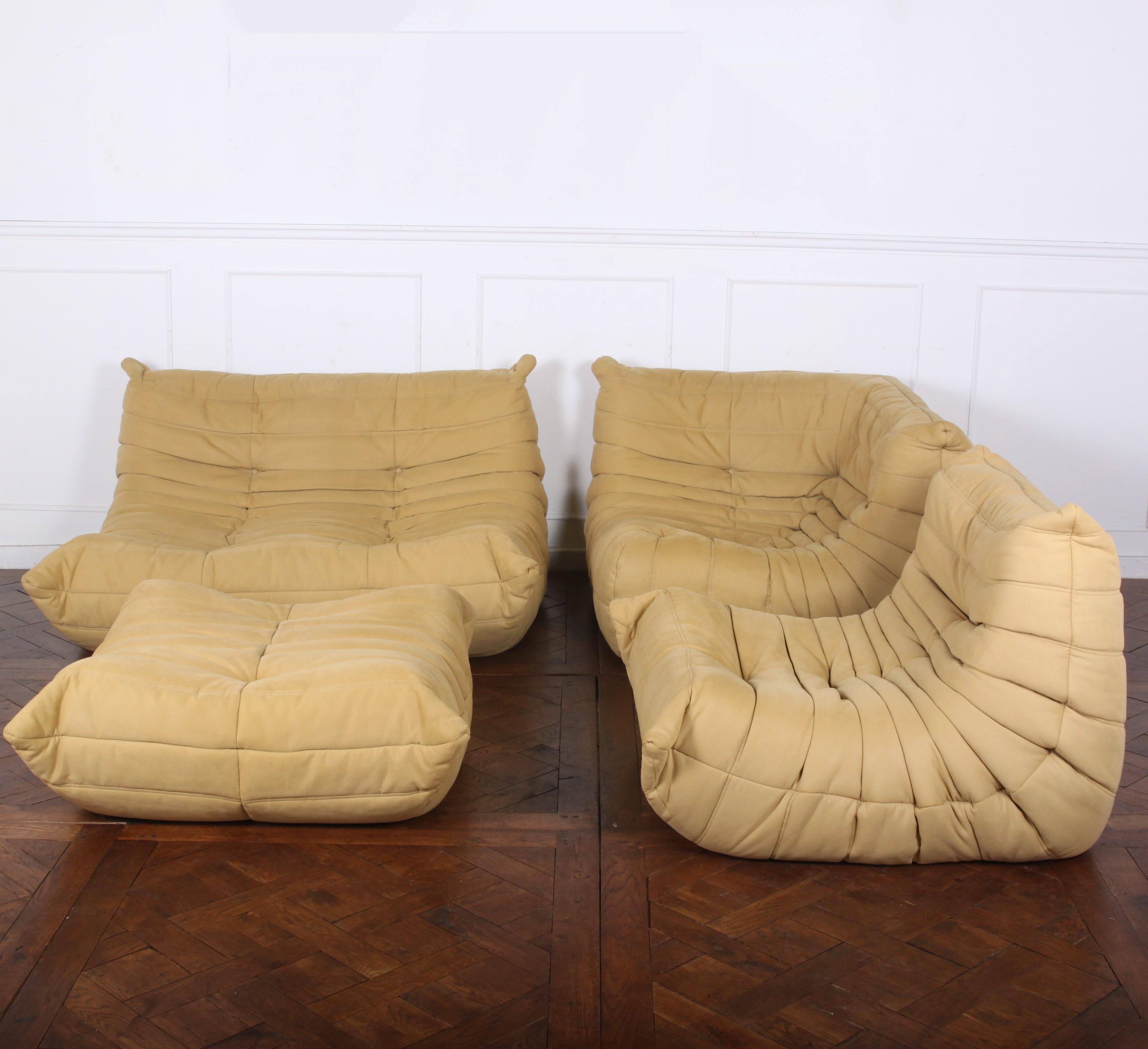 A four-piece vintage ‘Togo’ sofa suite in beige microfiber, consisting of a sofa, corner chair, chair, and pouf, all in perfect original condition. This iconic sofa design was conceived in 1973 by Michel Ducaroy for the French maker Ligne Roset and