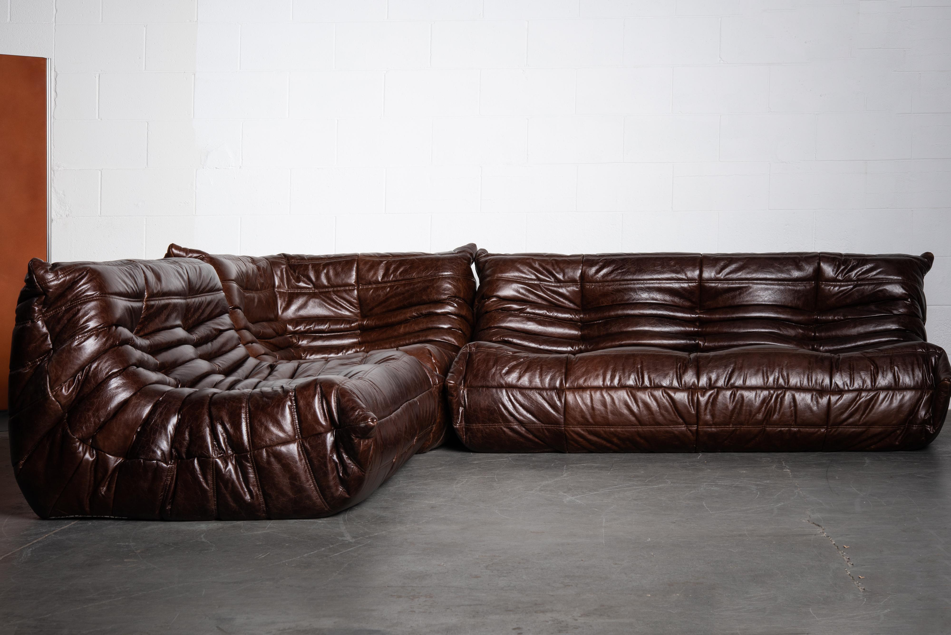 This incredible three (3) piece dark brown leather Togo sectional living room set, was designed by Michel Ducaroy in 1973 for Ligne Roset, France. Comprised of a three-seat sofa, two-seater loveseat and a corner seat. Signed with Ligne Roset