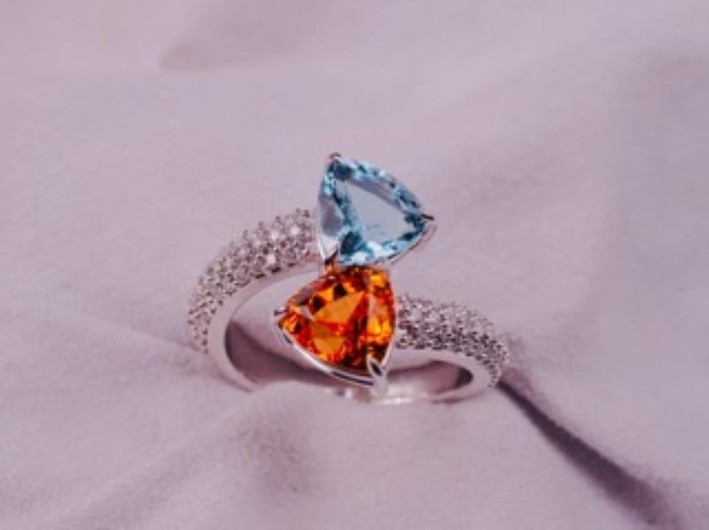Stunning toi-et-moi ring featuring fiery spessartite and a deep aqua blue aquamarine. Set in 18K white gold, with 0.54 tcw diamond ornamenting the shank, this piece is a true show stopper.  Spessartite is a fine stones of 2.90 carats and the