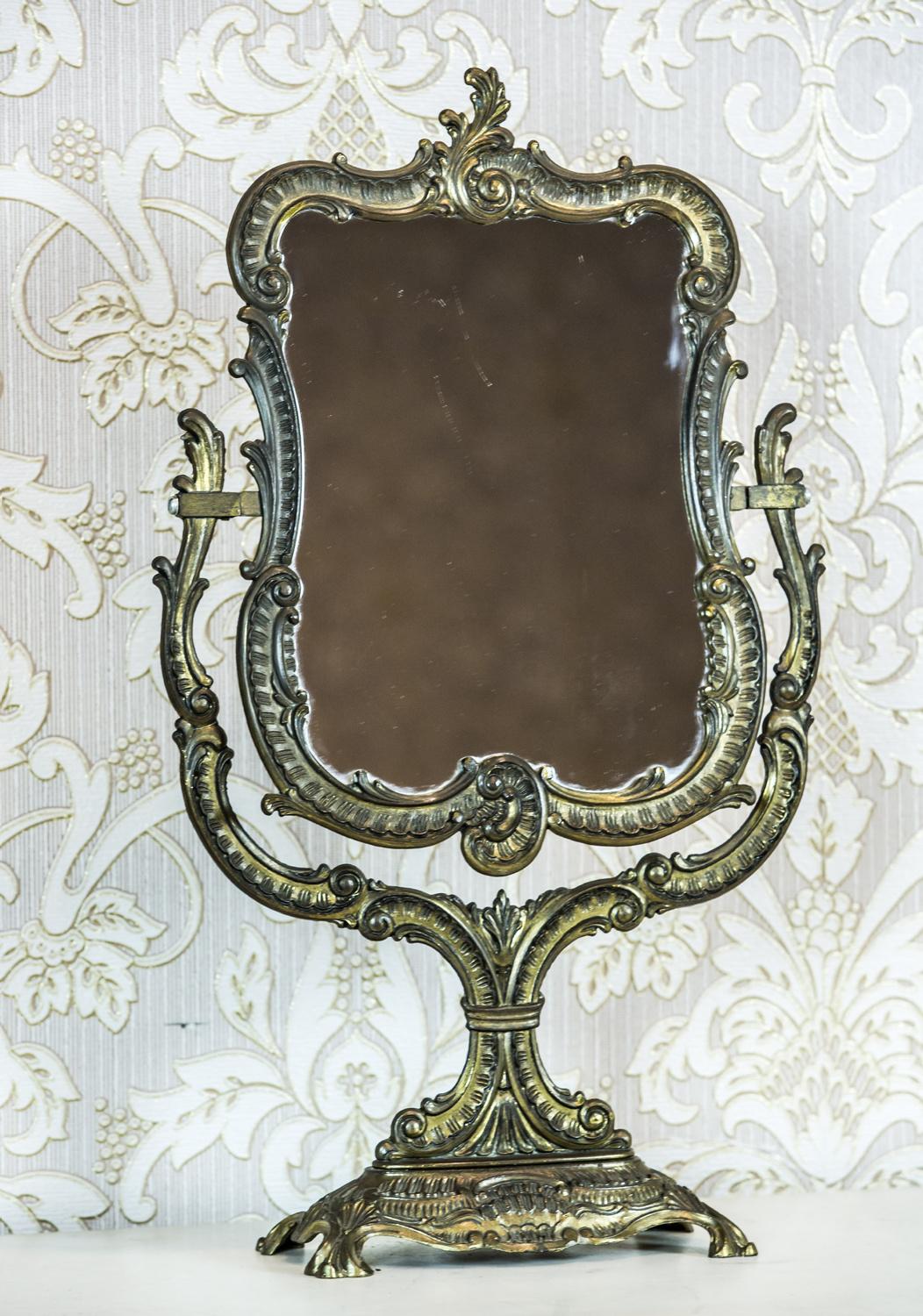 We present you this portable toilet mirror in a decorative, brass frame in the Neo-Rococo style.
The mirror is movable, hung on side stands, which are connected at the bottom with the base.

Presented item is in very good condition. The metal