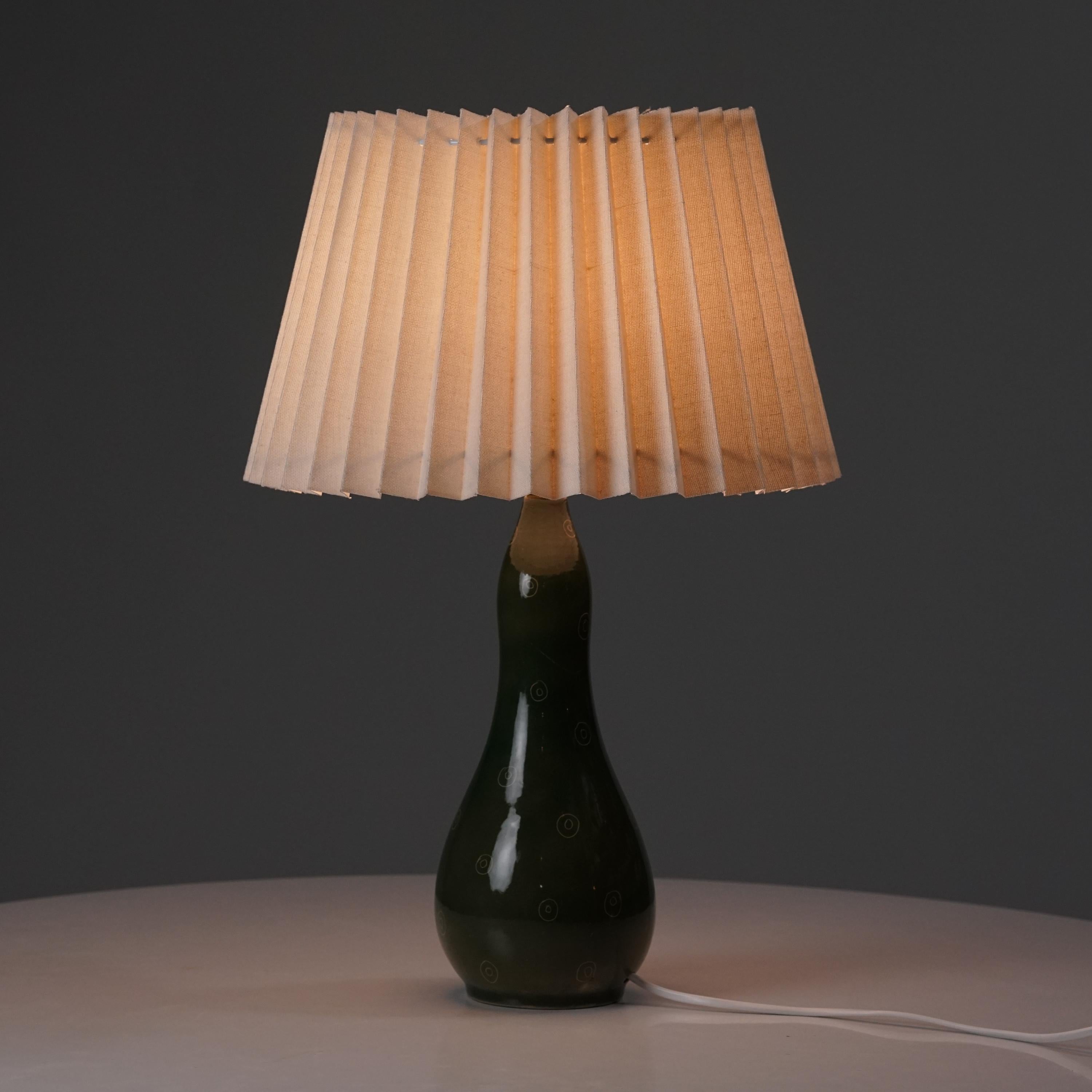 Toini Muona ceramic table lamp manufactured by Arabia, 1950s. Glazed ceramic frame, fabric shade. Marked. Good vintage condition, minor patina consistent with age and use. 

Toini Muona was a pioneer of modernism. Muona represented the sharpest edge