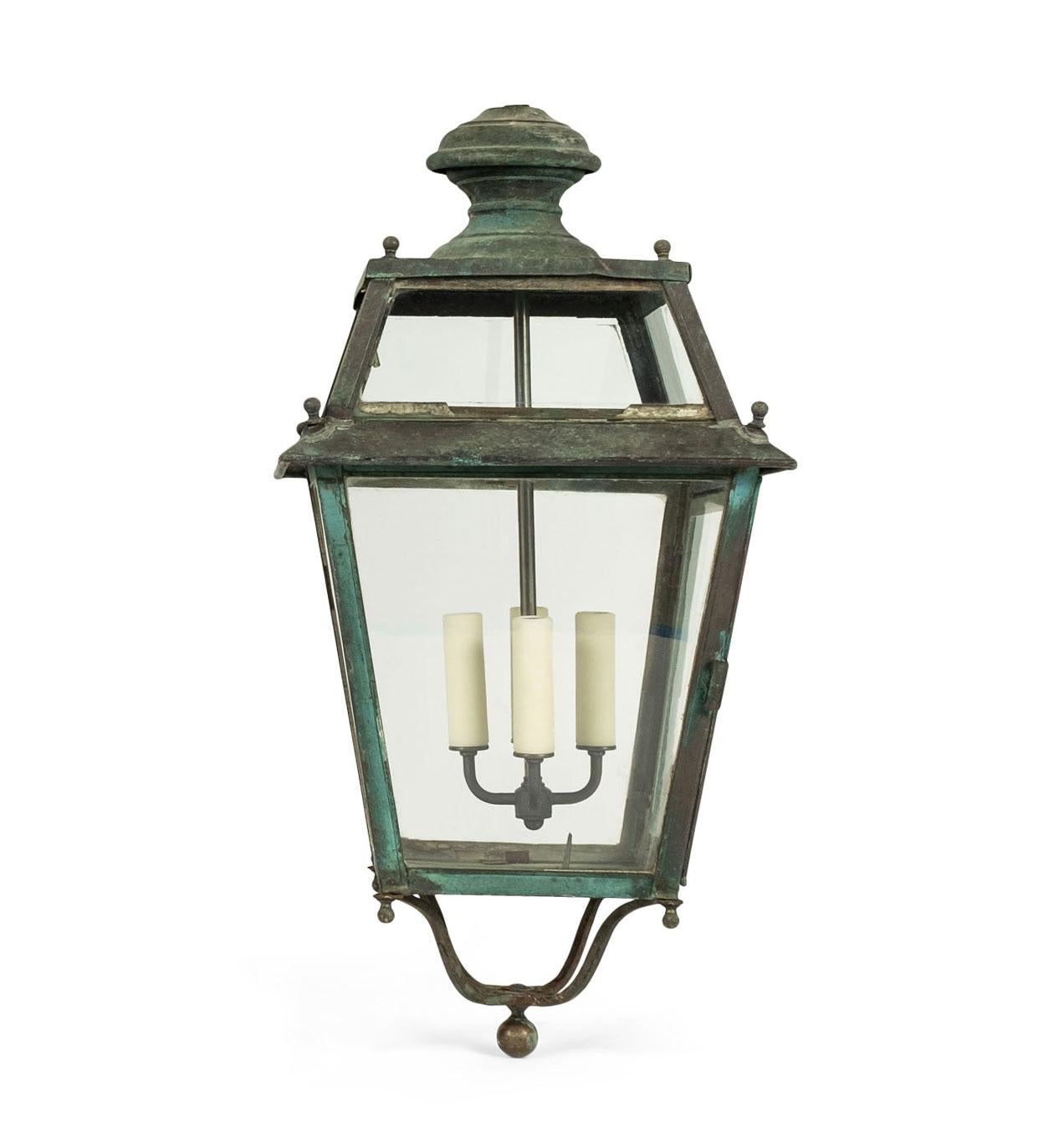 Tole and glass French lanterns dating to the 19th century. Heavy iron frame. Remnants of bluish-verdigris paint. Original wavy glass panels. Newly-wired for use within the USA with four candelabra-size sockets. Includes chain and canopies.