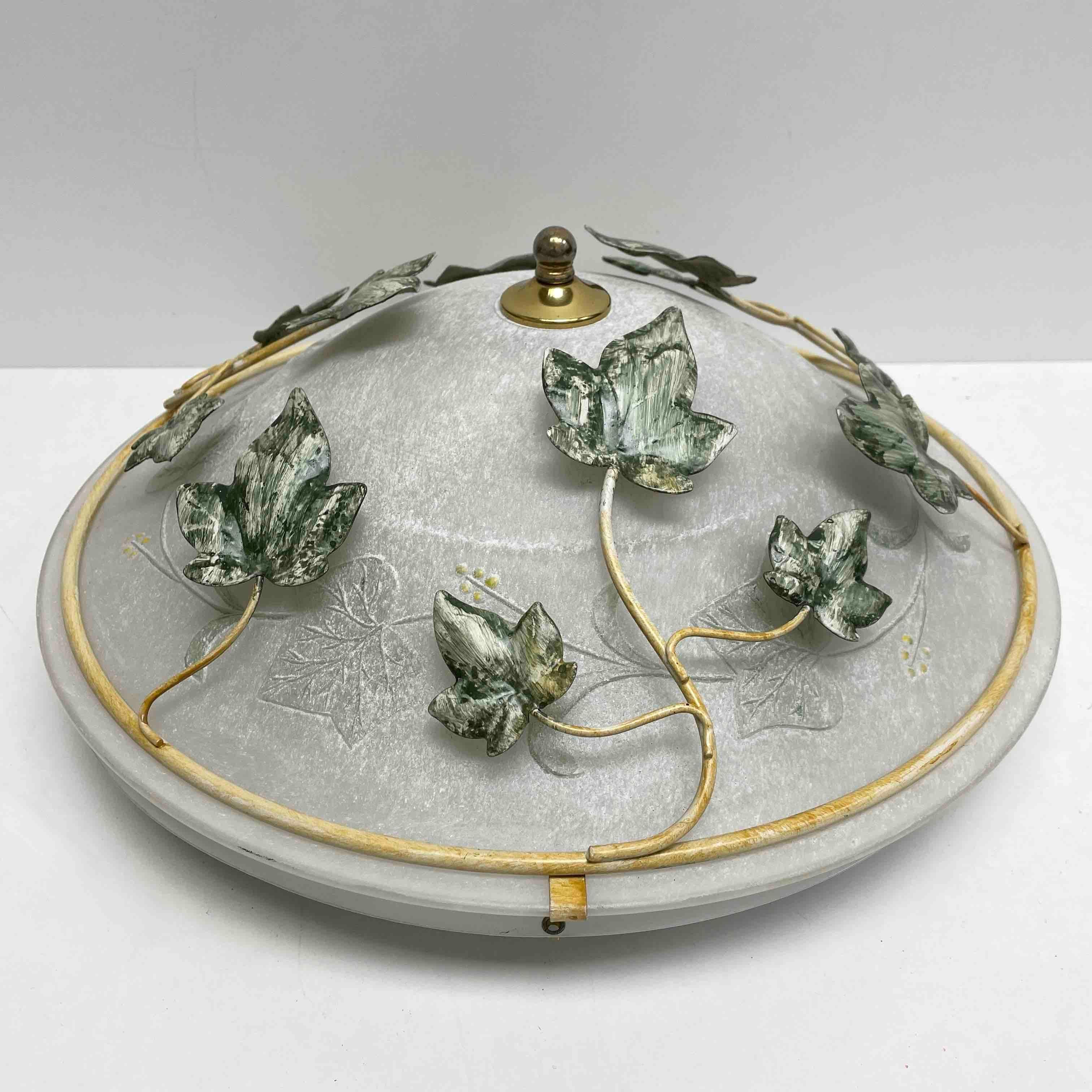 Add a touch of opulence to your home with this charming flush mount. Perfect green metal leafs to enhance any chic or eclectic home. The heavy glass cast in a mold has a satin finish and is decorated with leaves. The frosted glass emits a very warm,