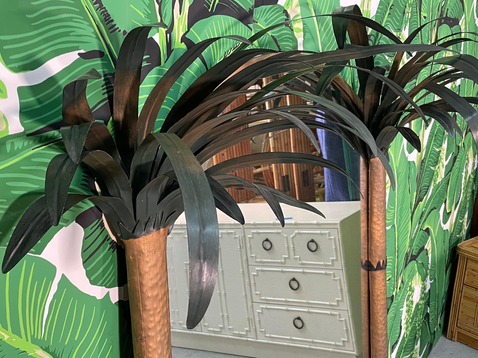 Large Hollywood Regency style wall mirror features full metal frame and double columns designed as palm trees with tole palm fronds. Very good vintage condition with only minor imperfections consistent with age (see photos). Total measurement is