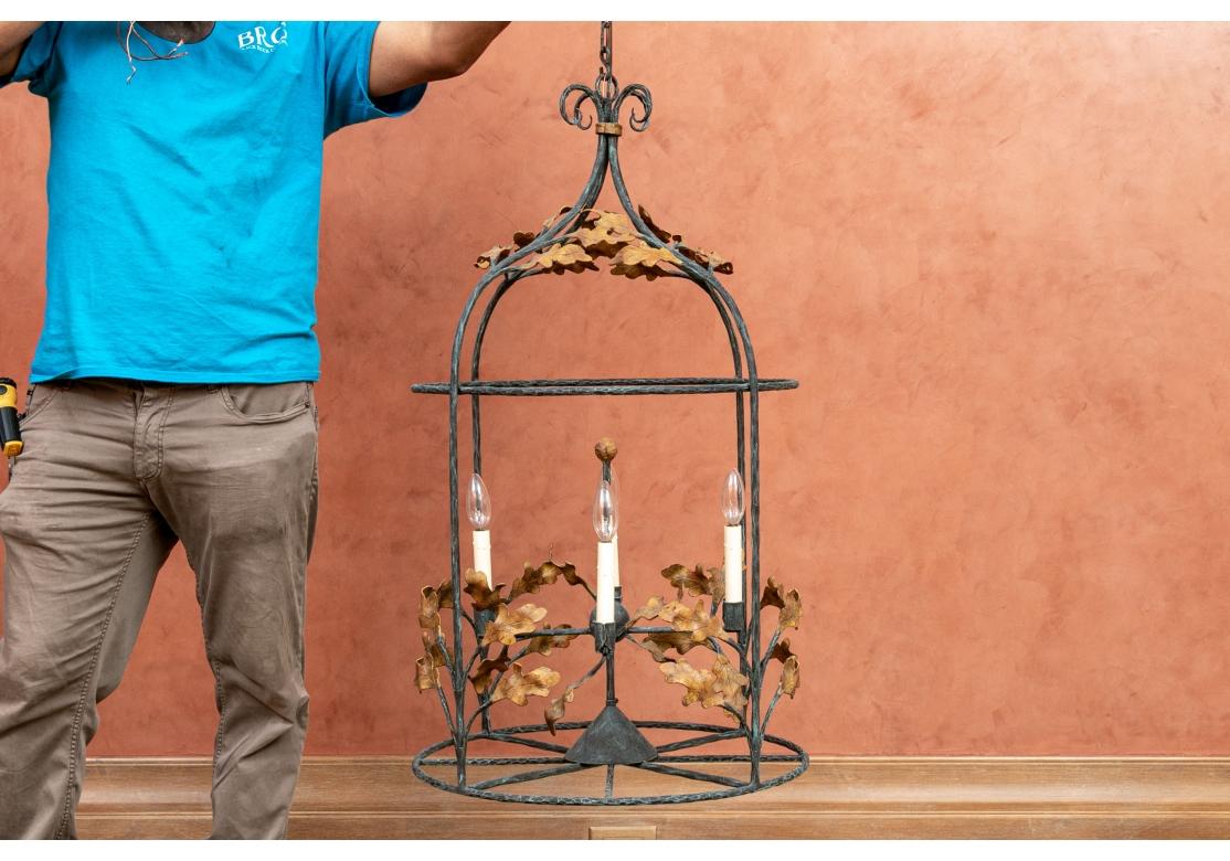 A well made and very decorative Openwork Birdcage form Iron Chandelier with fine form and color. A black and verdigris hammered metal frame with four lights decorated with rust tone oak leaves on branches overall. With a scrolled top and wheel form