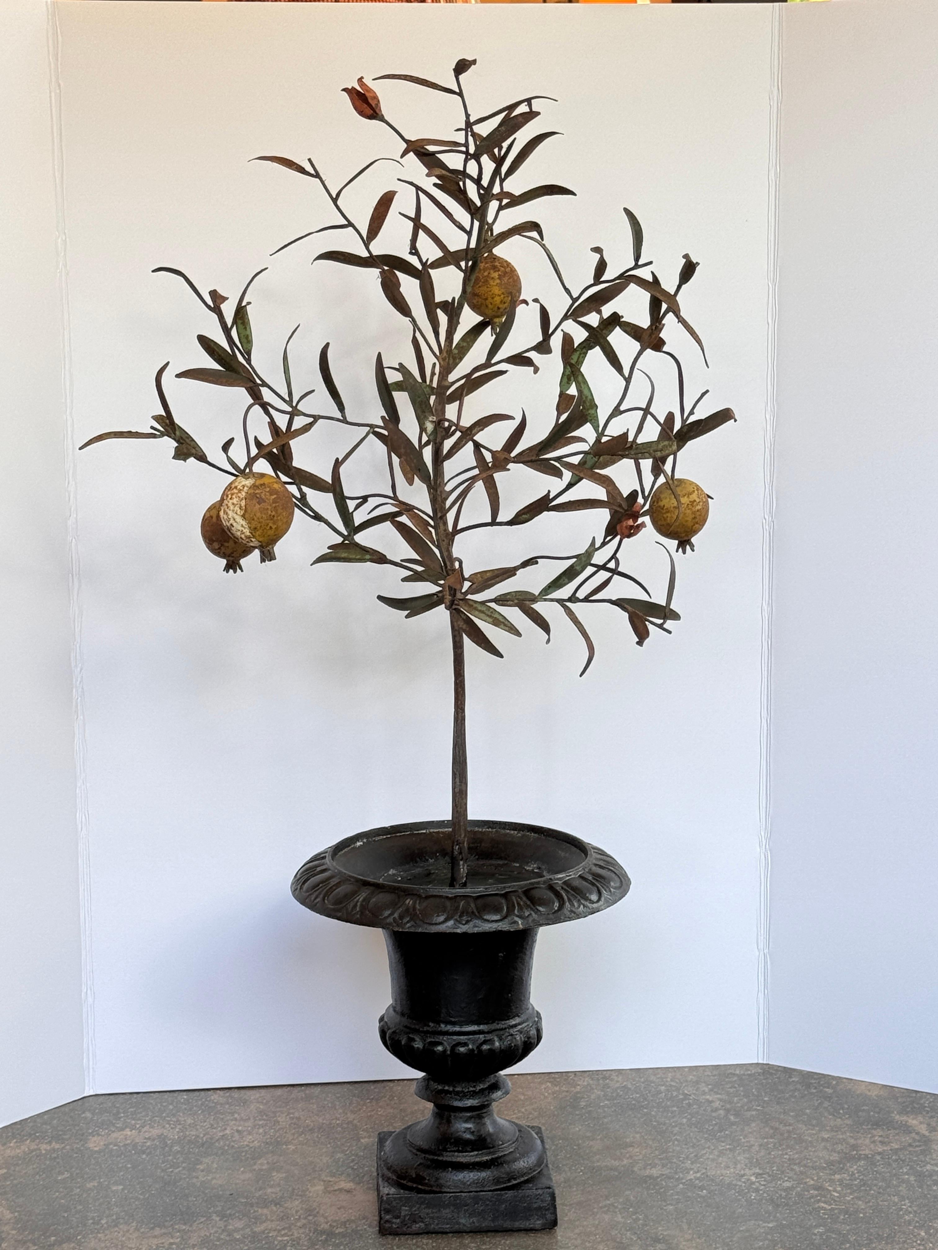 Dekorativer Tannenbaum mit Zweigen aus Blättern und Granatäpfeln, präsentiert in einer schwarz lackierten Urne mit geformten Details. Die naturalistische Form und die gealterte Patina verleihen diesem Stück eine starke dekorative Präsenz.
