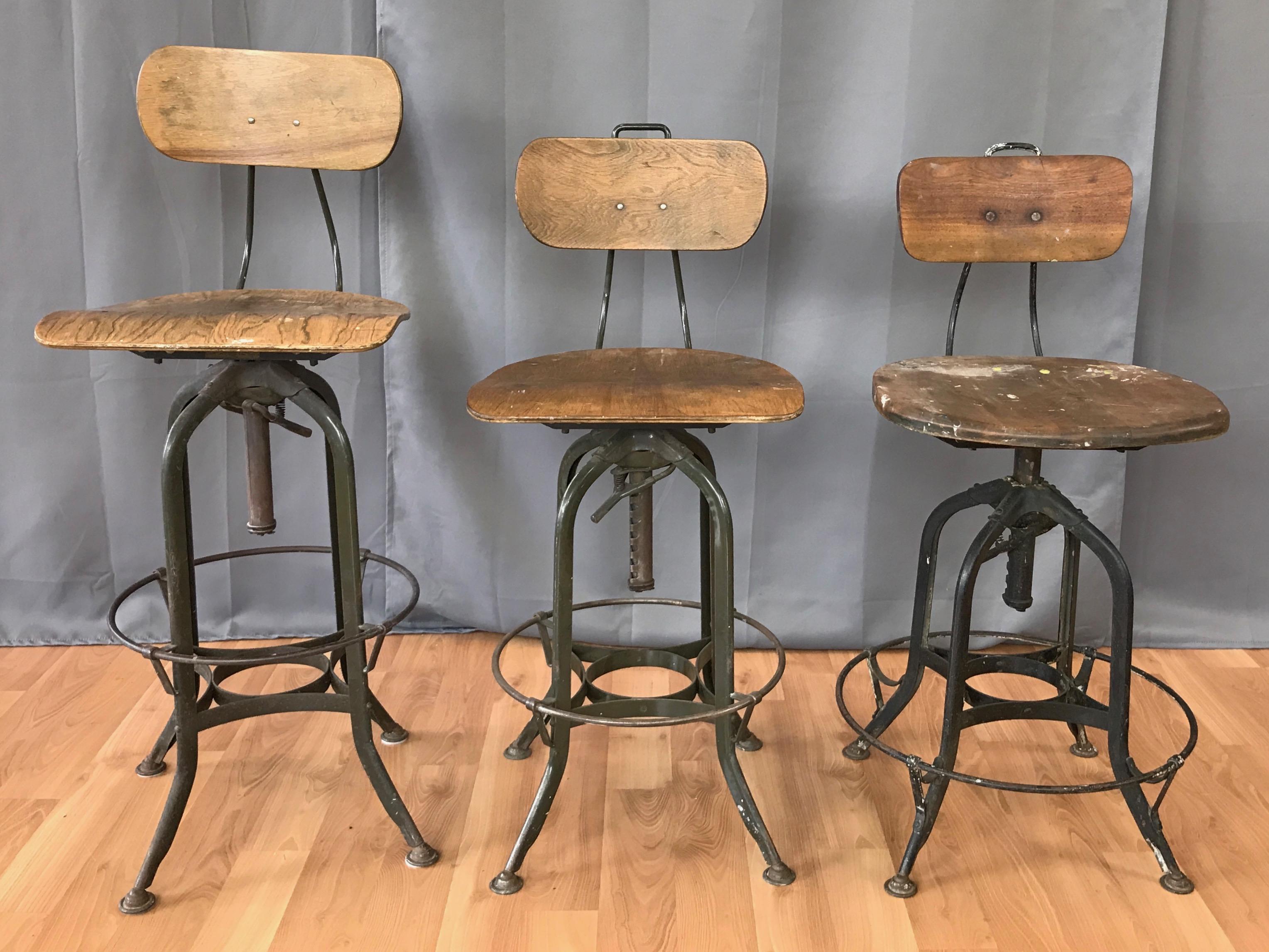 Two 1930s industrial adjustable height swivel stools with backs by Toledo Metal Furniture Company, offered individually. Stool pictured on the far right has sold.

Green enameled steel base and frame with adjustable height bentwood swivel seats.