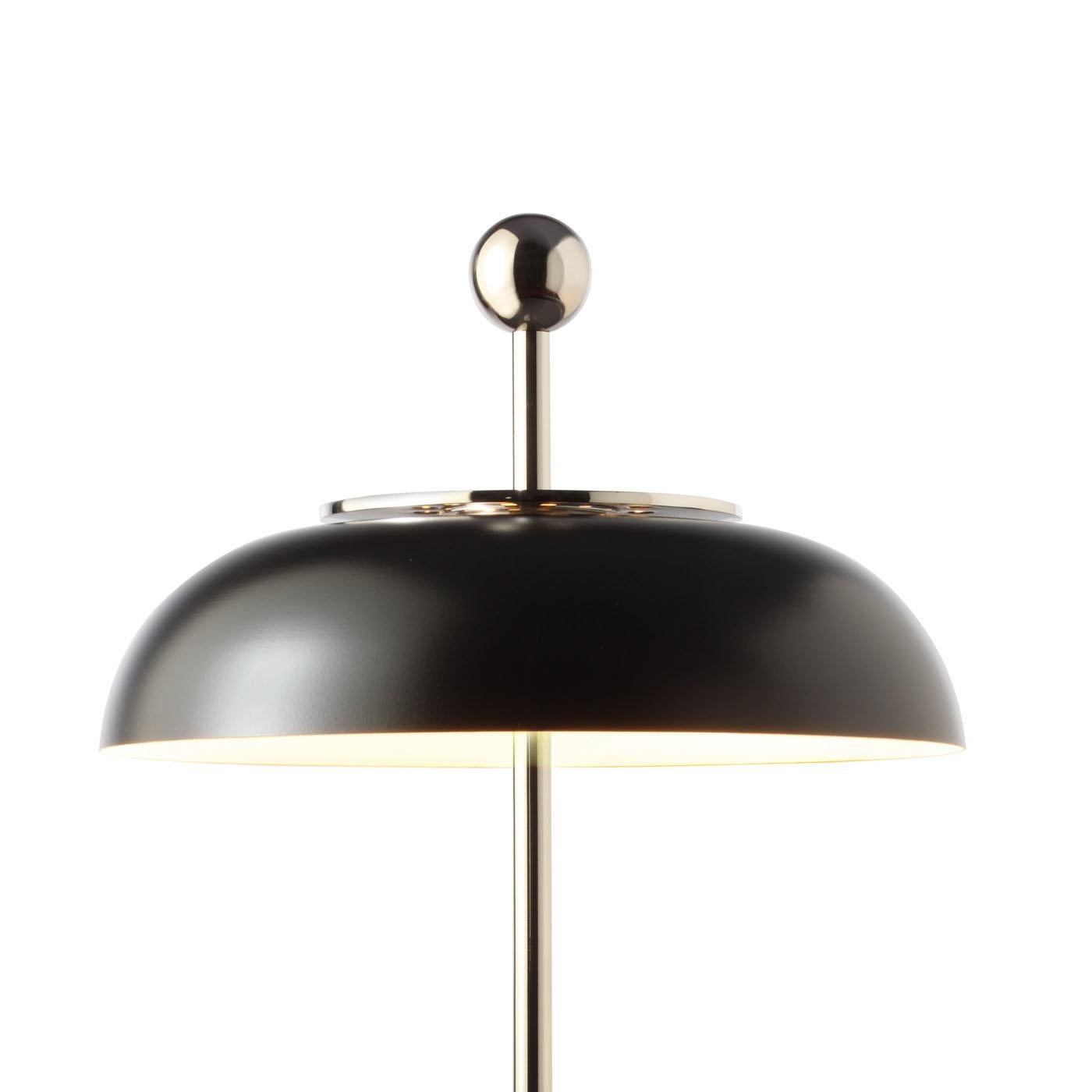 The structure of this elegant desk lamp is made entirely in metal and consists of a round base and a shaft that runs vertically and continues over the shade ending in a round top. The shade, a sophisticated semi-spherical metal element facing